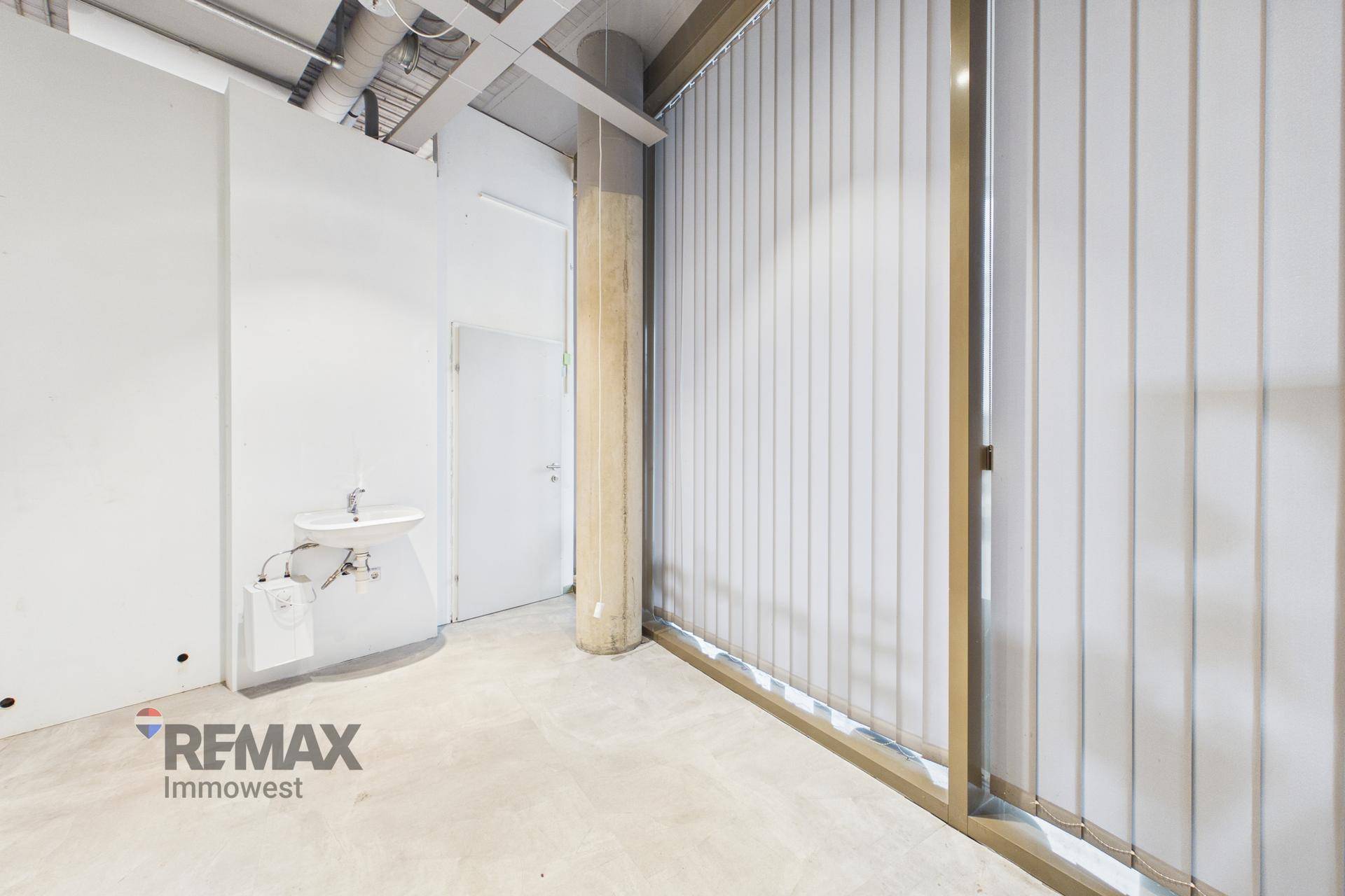 Kleiner Raum mit Waschbecken, Betonpfeiler und Fenster mit vertikalen Jalousien, ideal für Nebenfunktionen oder eine Teeküche.