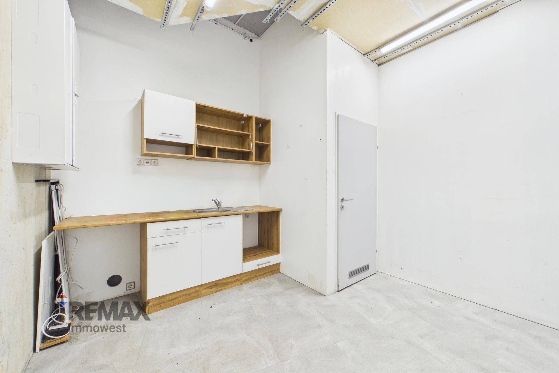 Küchenzeile mit Holz-Arbeitsplatte und weißen Unterschränken in einem hellen Raum mit Tür und viel Potenzial.