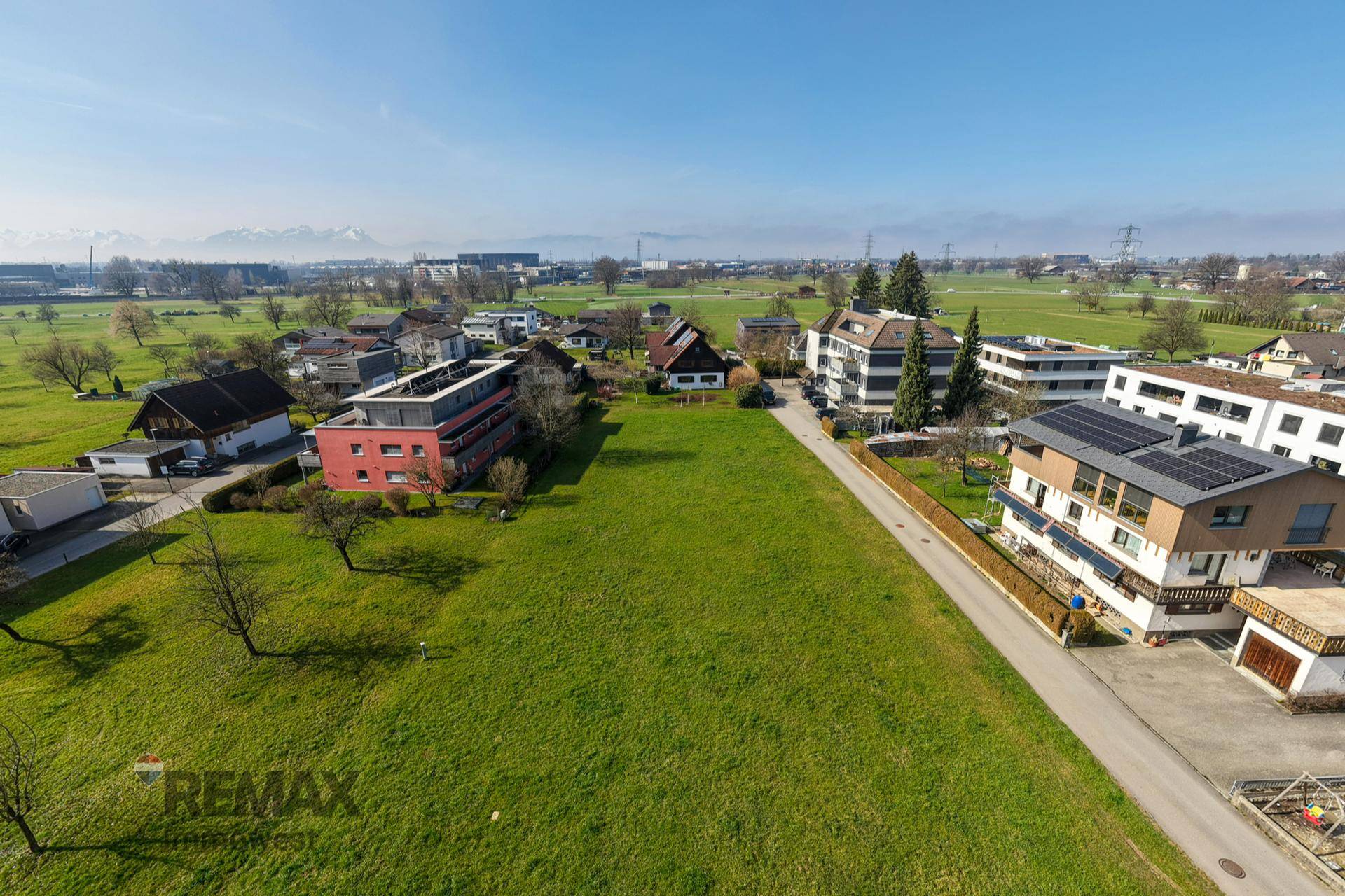 Weitläufige Luftaufnahme der ländlichen Umgebung mit grünen Feldern und Bergsicht in der Ferne.