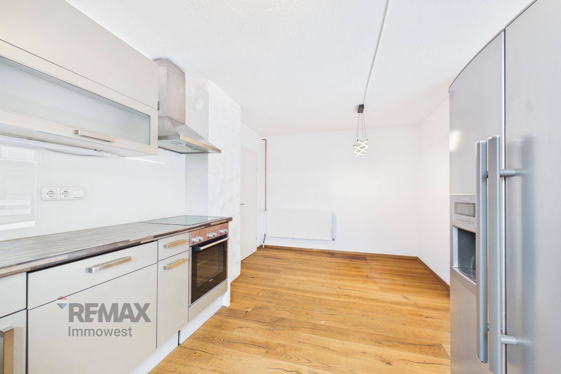 Funktionale Küche mit hellgrauen Schränken, Backofen und einem großen Kühlschrank.