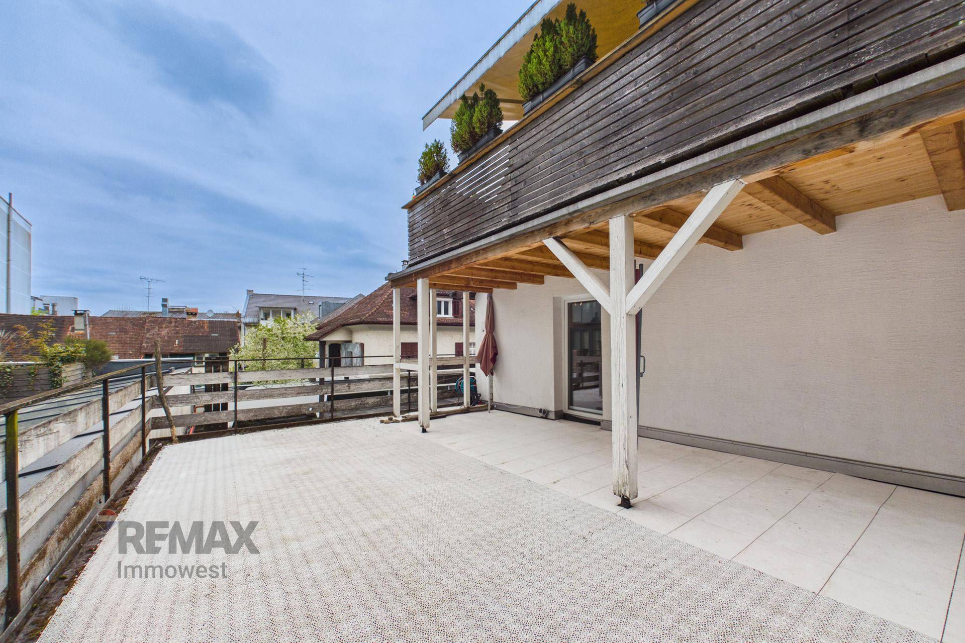 Weitläufige Terrasse mit Fliesenboden und Holzverkleidung, bietet viel Platz im Freien.