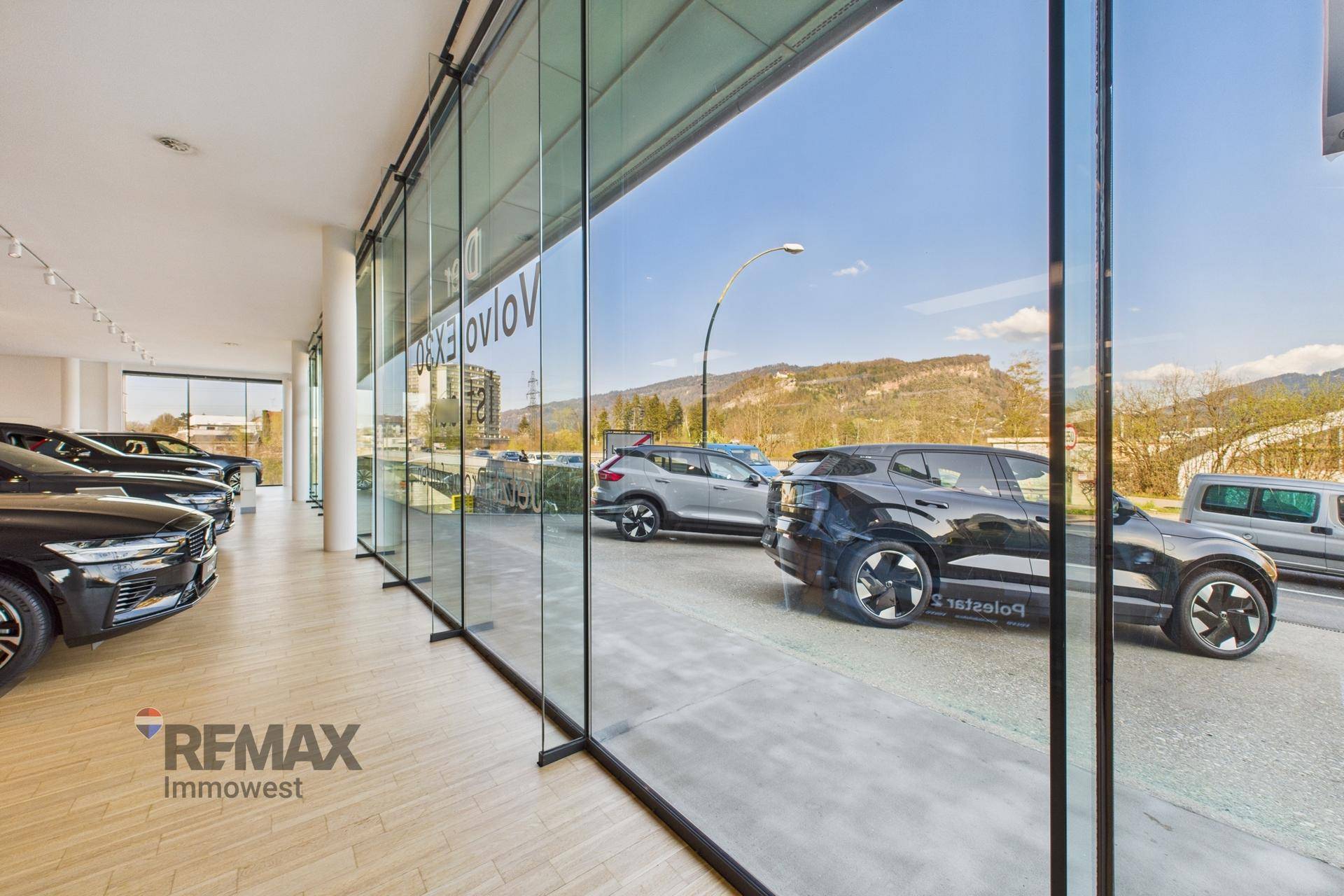 Showroom mit großen Glasfronten, die einen Blick auf die Straße und die umliegende Landschaft ermöglichen.
