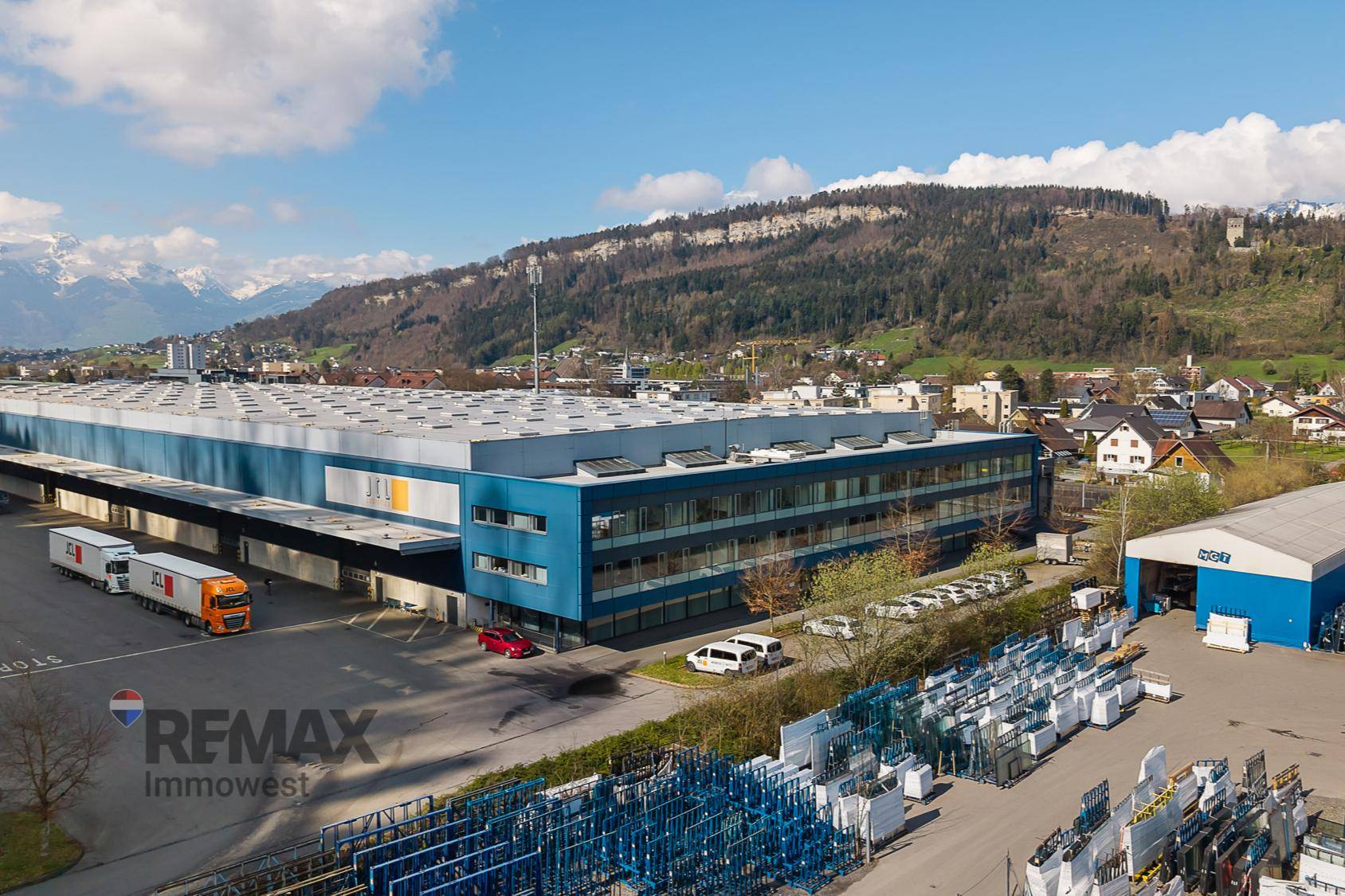 Luftaufnahme eines modernen Büro- und Lagergebäudes in einer bergigen Landschaft.