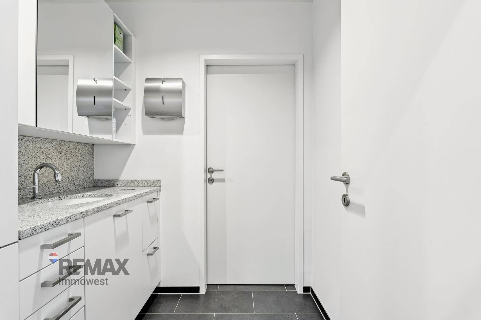 Funktionaler Raum mit Waschbecken, Granit-Arbeitsplatte und weißen Schränken, ideal für den Gebrauch.