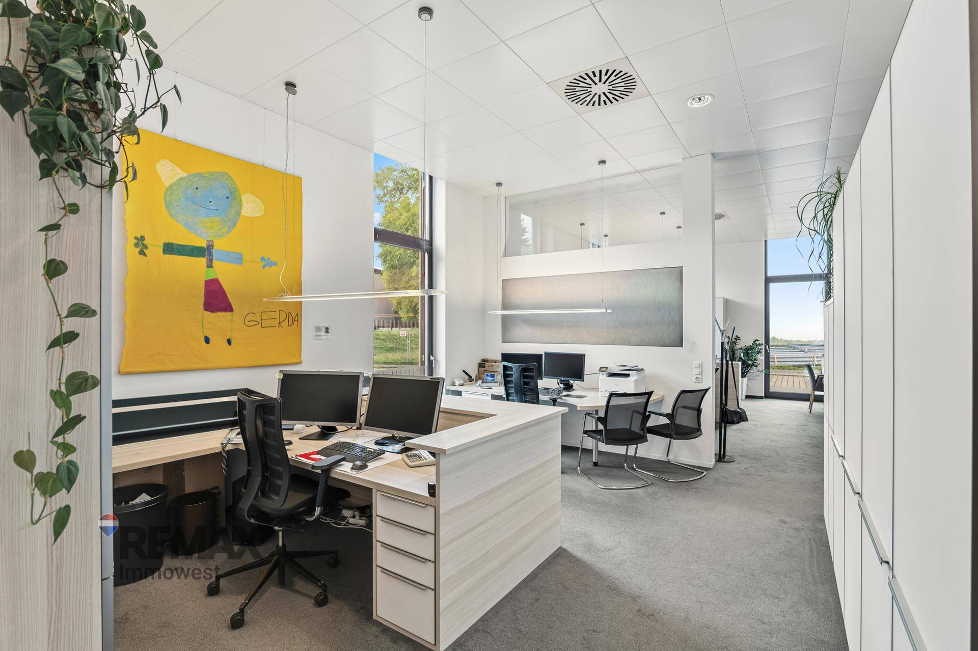 Großes, offenes Büro mit mehreren Arbeitsbereichen, viel Tageslicht und modernen Einbauten.