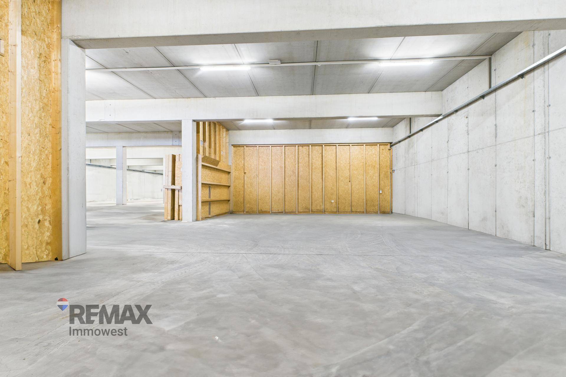 Lagerbereich mit eingebauten Holzregalen und Trennwänden entlang der Betonwand, ideal für zusätzliche Lagerung.