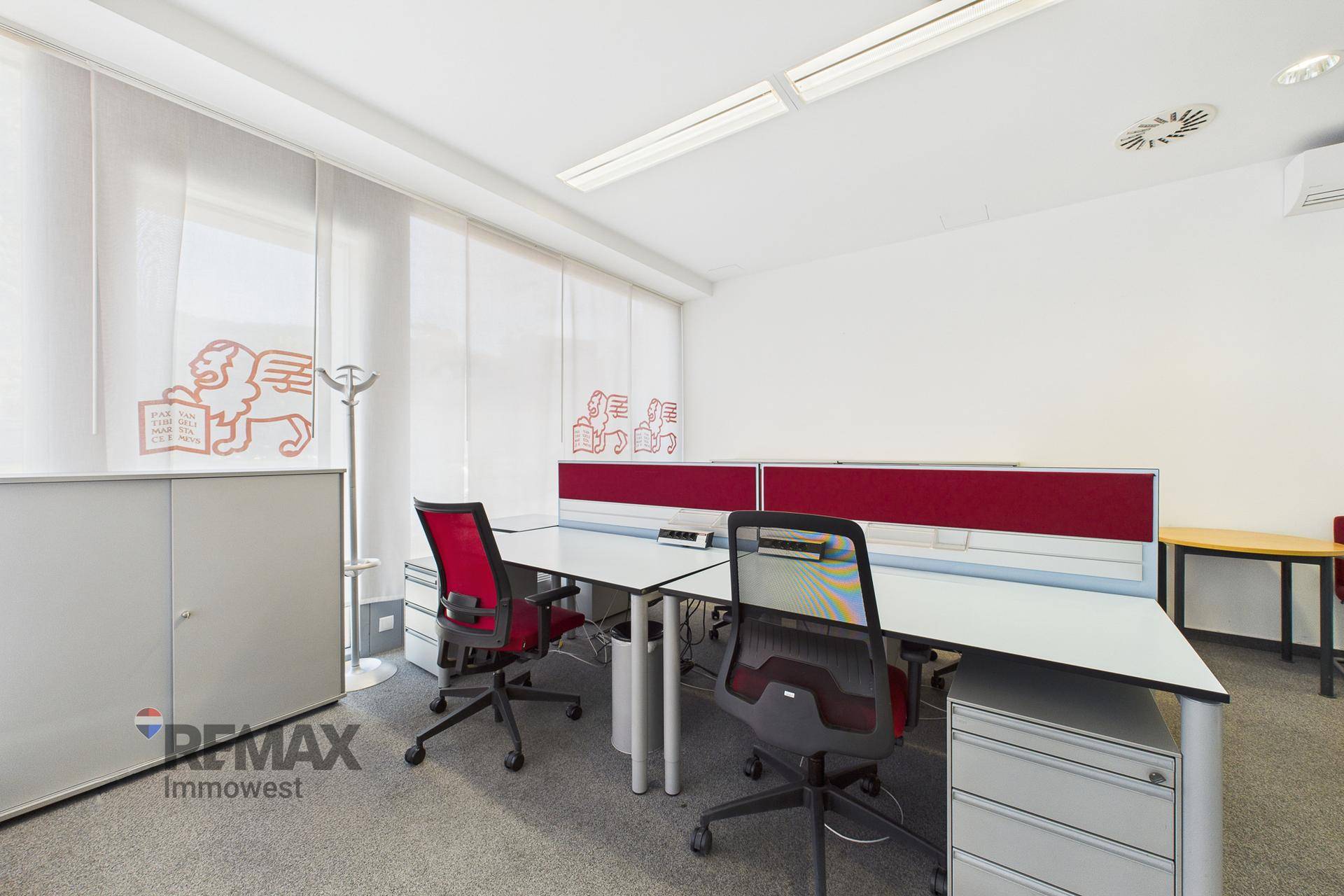 Offener Bürobereich mit zwei Arbeitsplätzen, Teppichboden und viel Tageslicht.