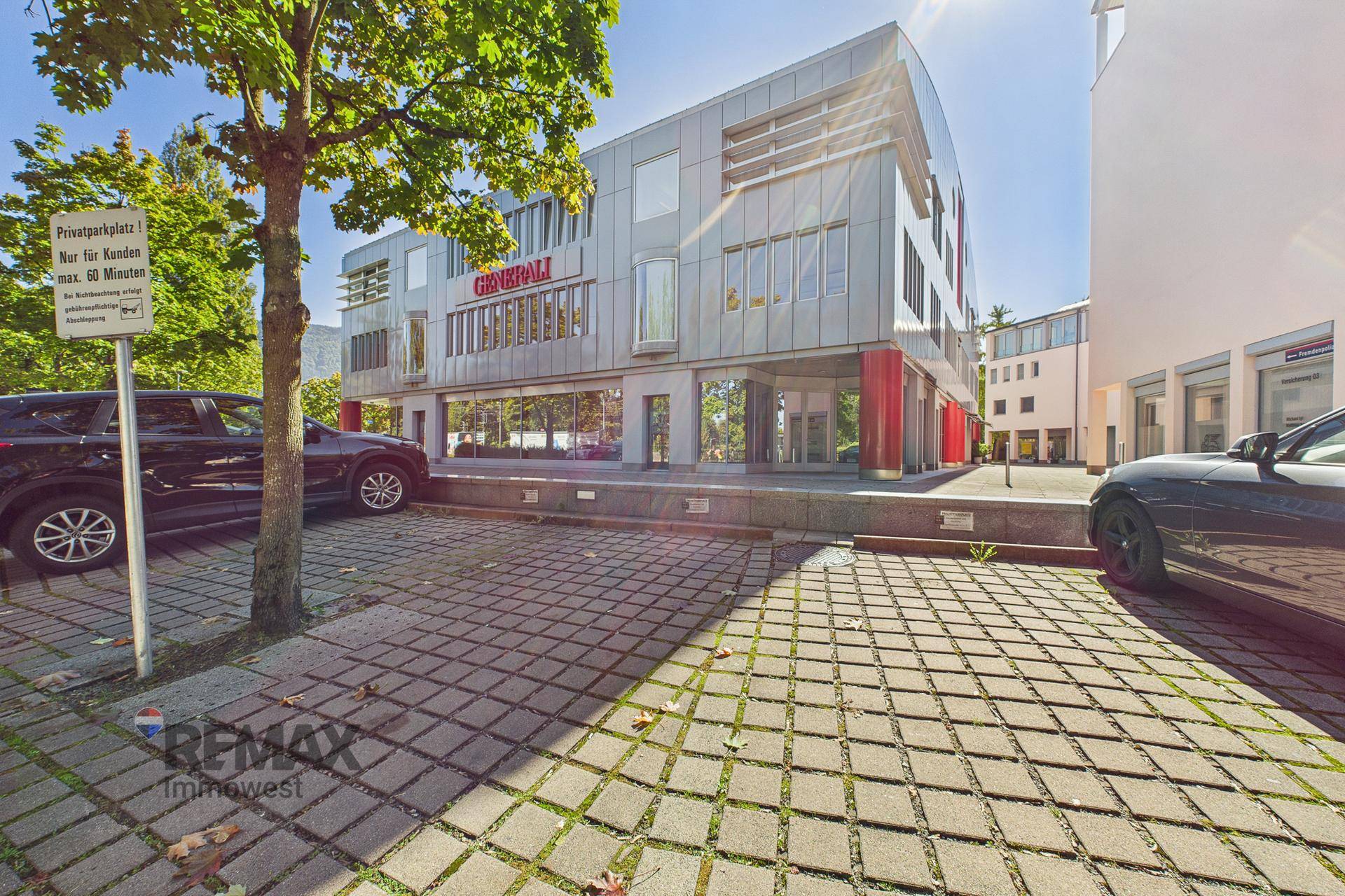 Außenansicht des modernen Bürogebäudes mit Parkplätzen und Bäumen im Vordergrund.