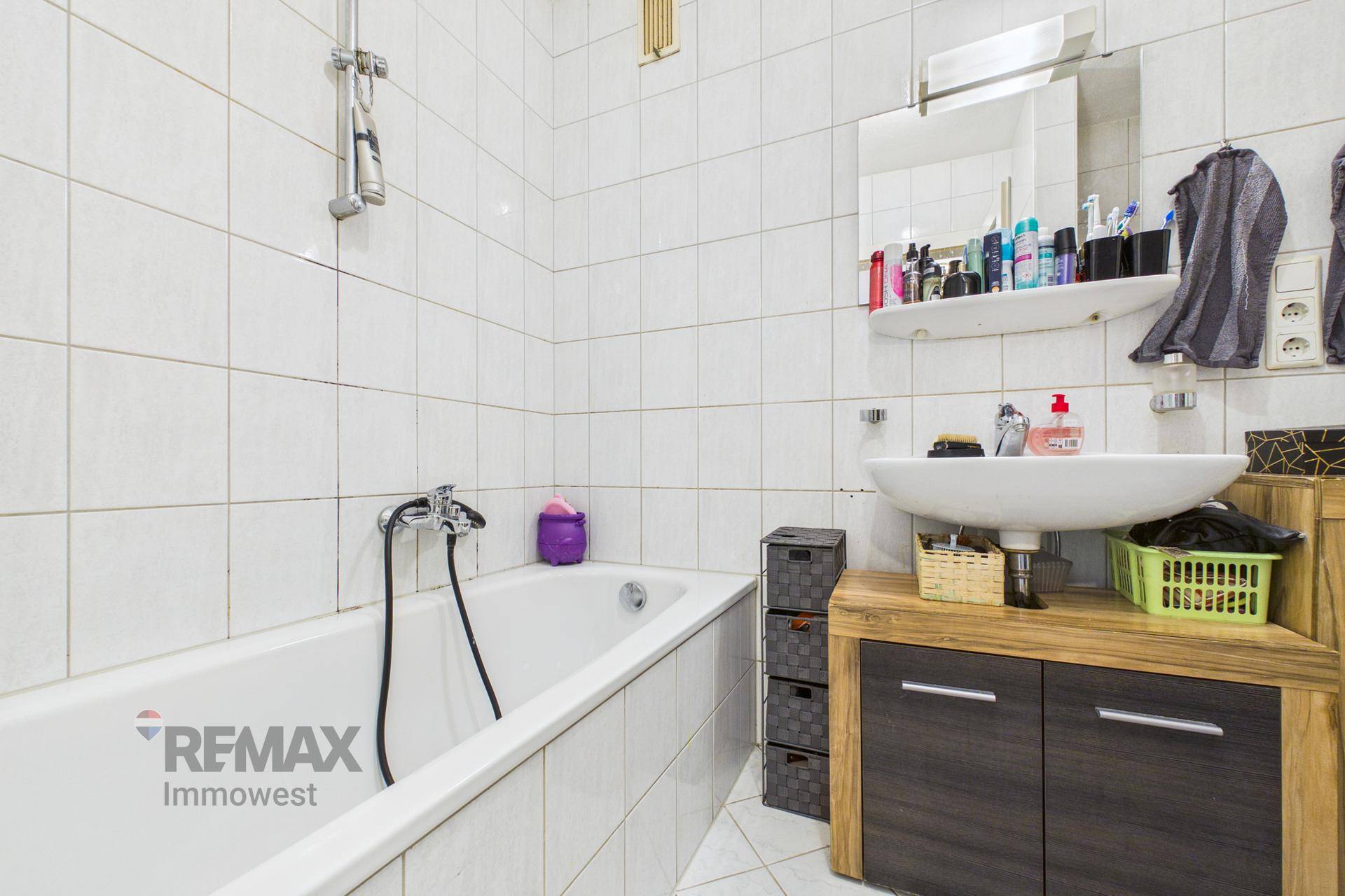Gefliestes Badezimmer mit Badewanne, Waschbecken und Spiegelschrank.