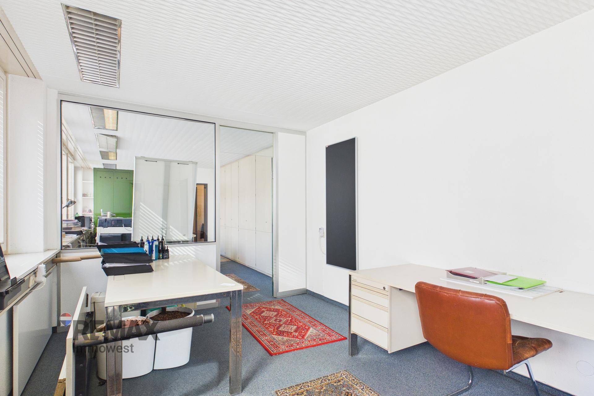 Büroraum mit Schreibtisch, Stuhl und einer schwarzen Wandtafel, die einen modernen Akzent setzt.