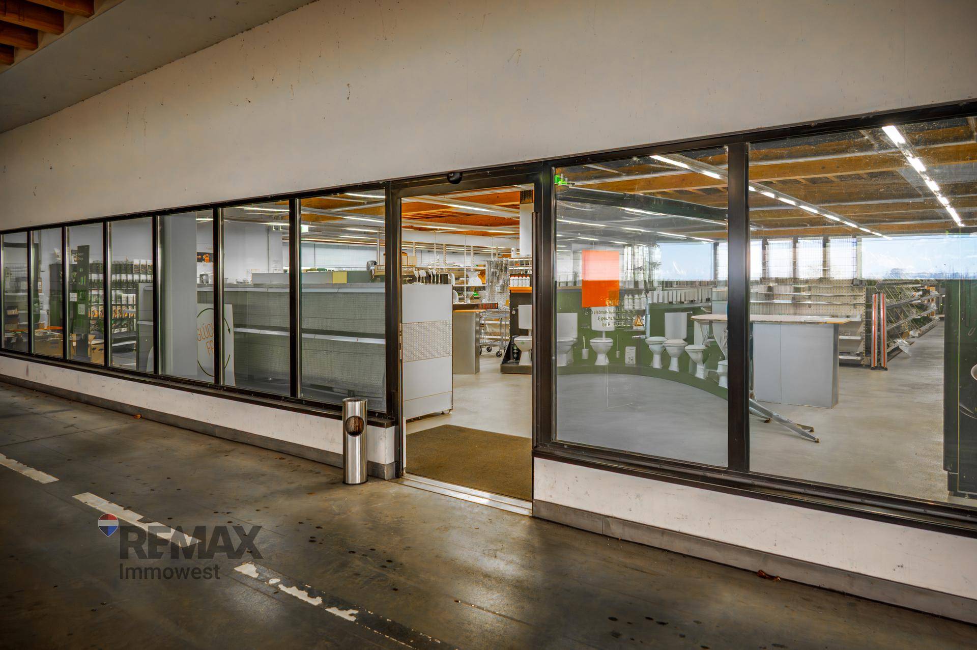 Weitläufiger Verkaufsraum mit großen Fensterfronten, der verschiedene Produkte ausstellt.