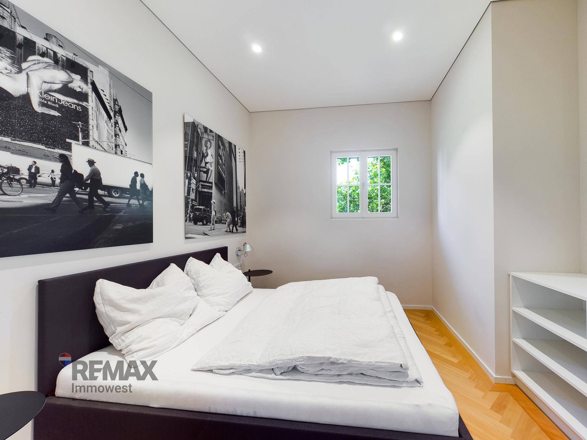 Gemütliches Schlafzimmer mit Doppelbett, Parkettboden und einem Fenster mit Grünblick.