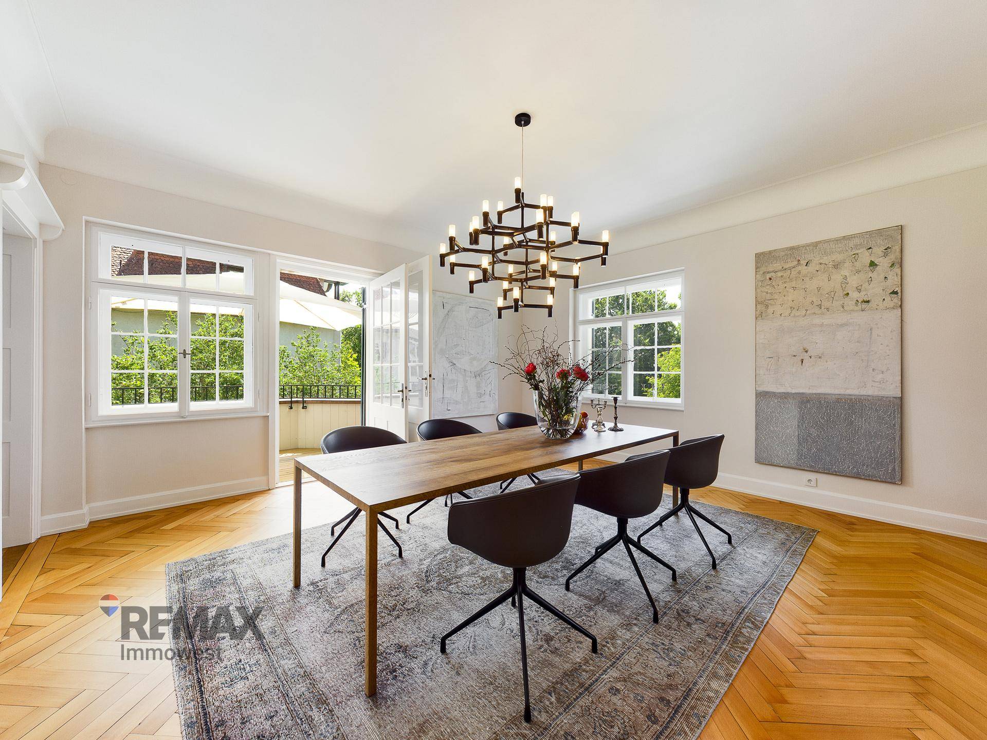 Eleganter Essbereich mit großem Holztisch, modernen Stühlen und Zugang zum Balkon.