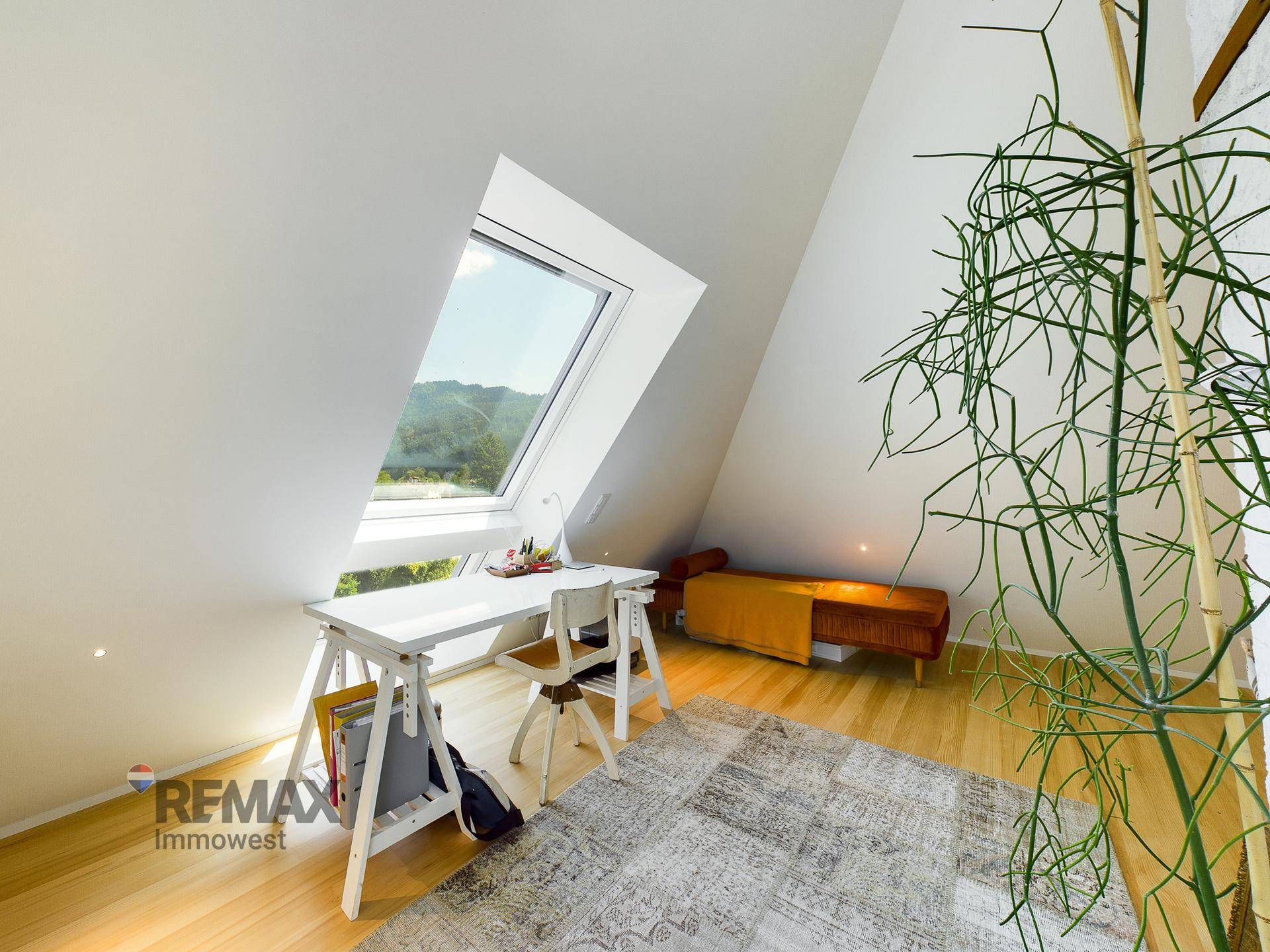 Helles Arbeitszimmer im Dachgeschoss mit Schreibtisch, Dachfenster und Holzboden.