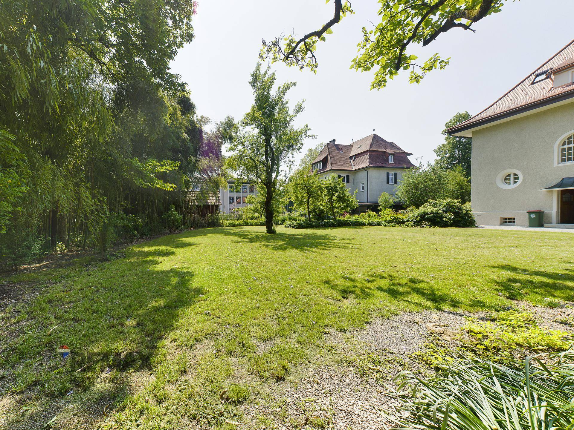 Weitläufiger Garten mit Rasenfläche und Blick auf das historische Gebäude im Hintergrund.