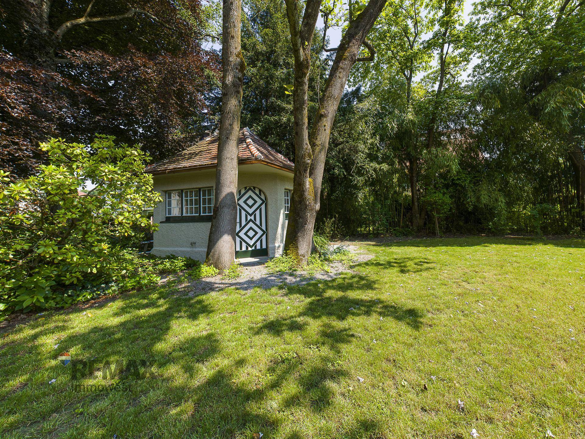 Idyllischer Gartenbereich mit altem Baumbestand und einem kleinen Gartenhaus.