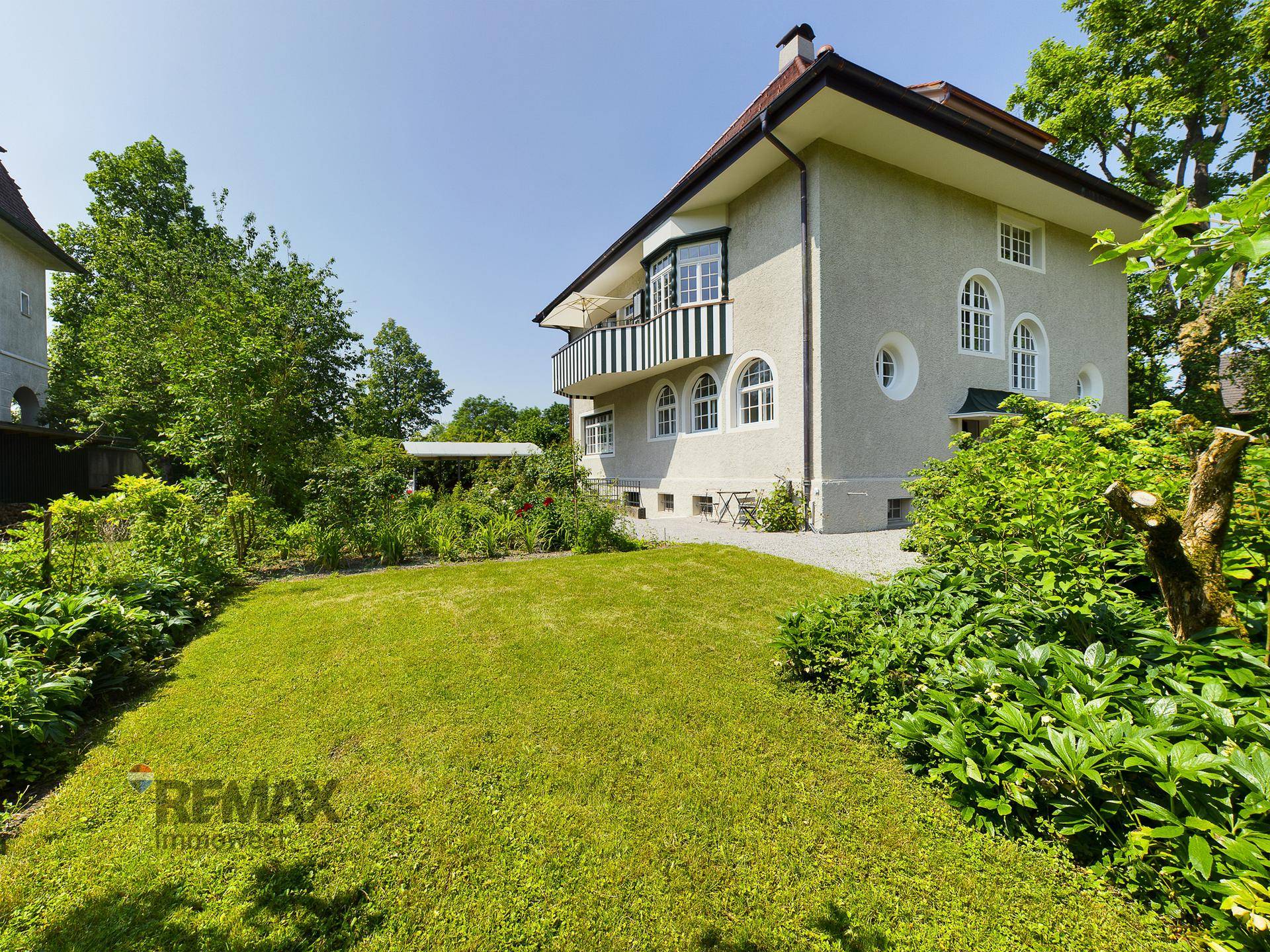 Seitenansicht der Villa mit gepflegtem Garten und üppiger Bepflanzung.