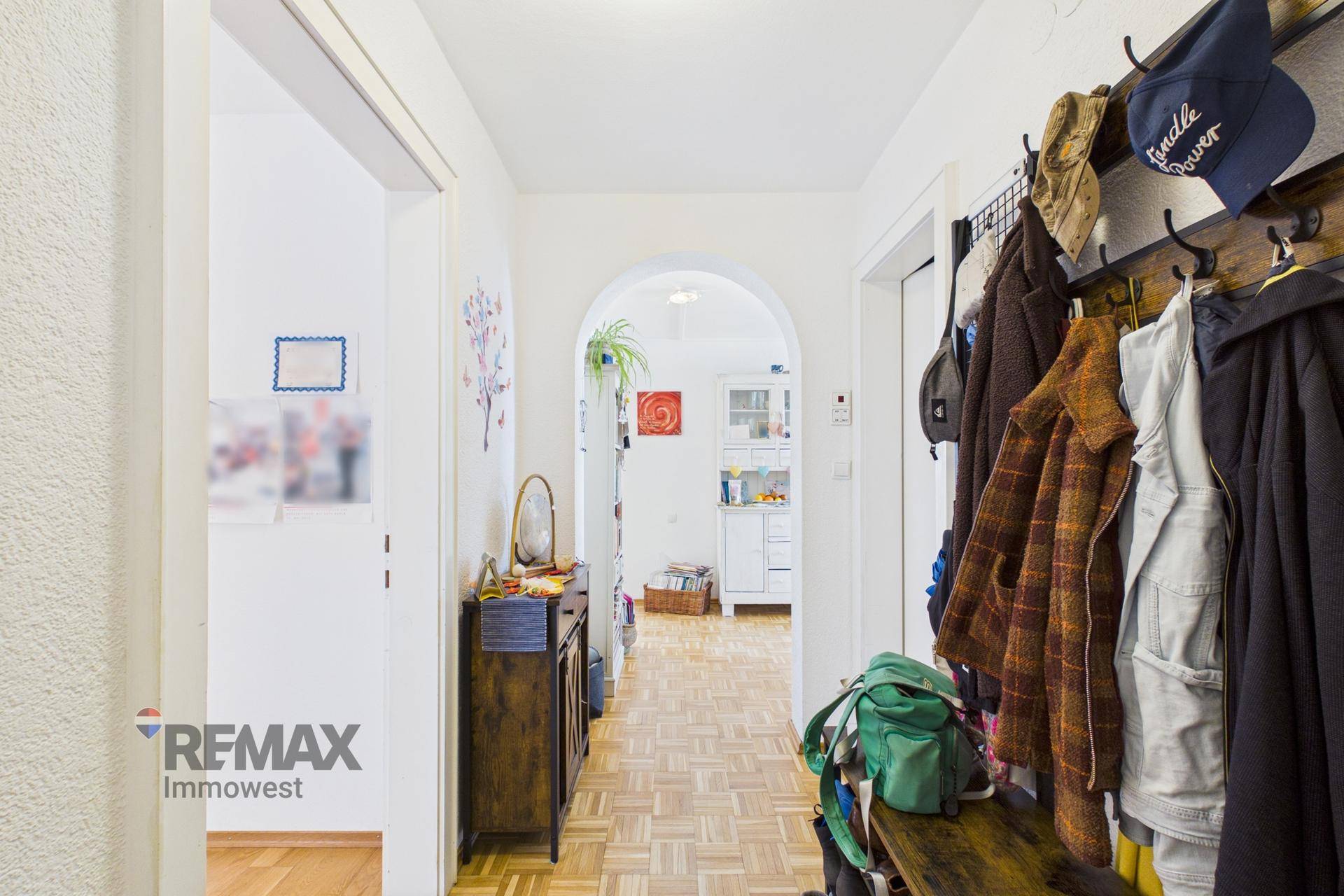 Heller Flur mit Parkettboden, Garderobe und Durchgang zu weiteren Räumen.