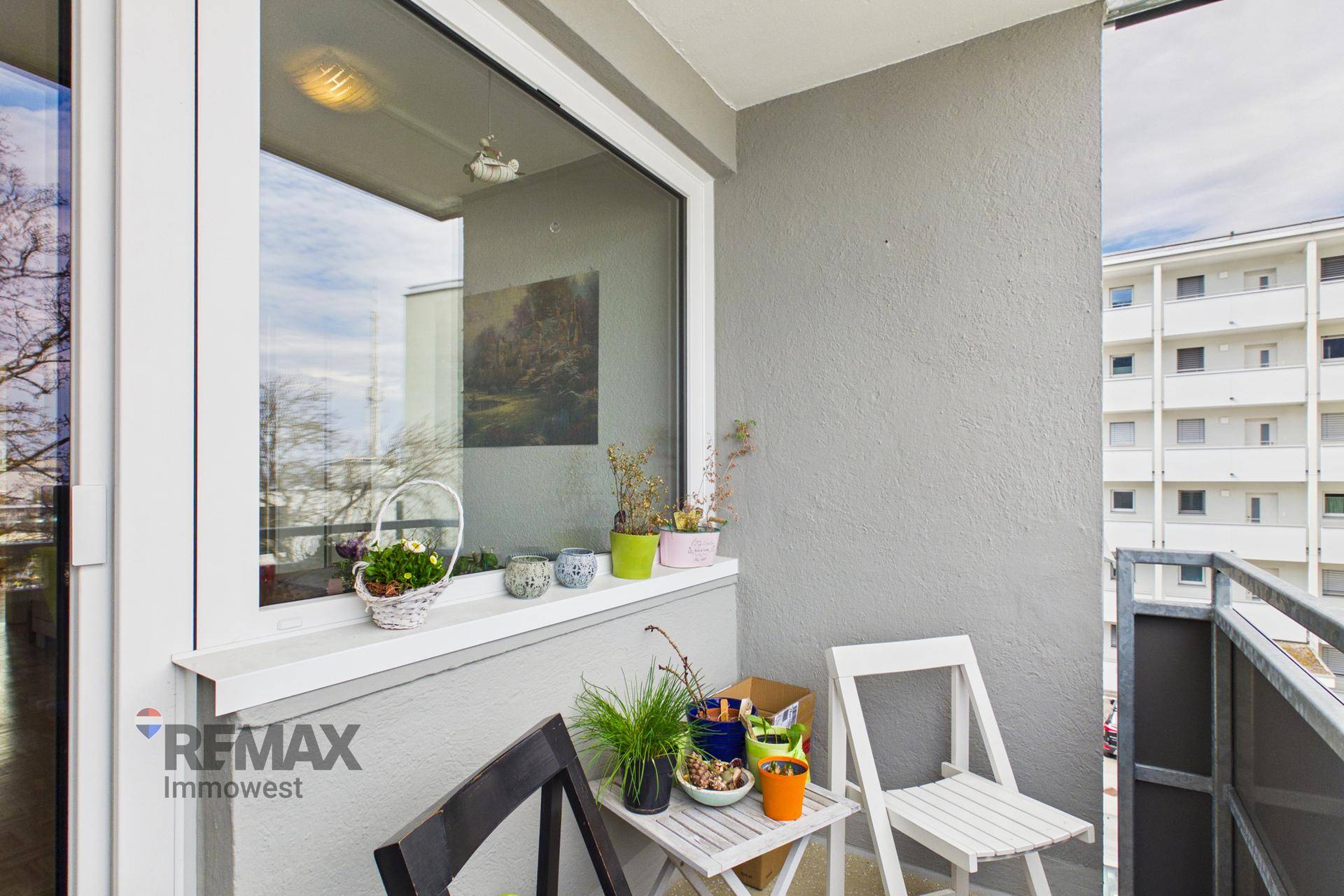 Kleiner Balkon mit Sitzgelegenheiten und Blick auf die umliegenden Gebäude.