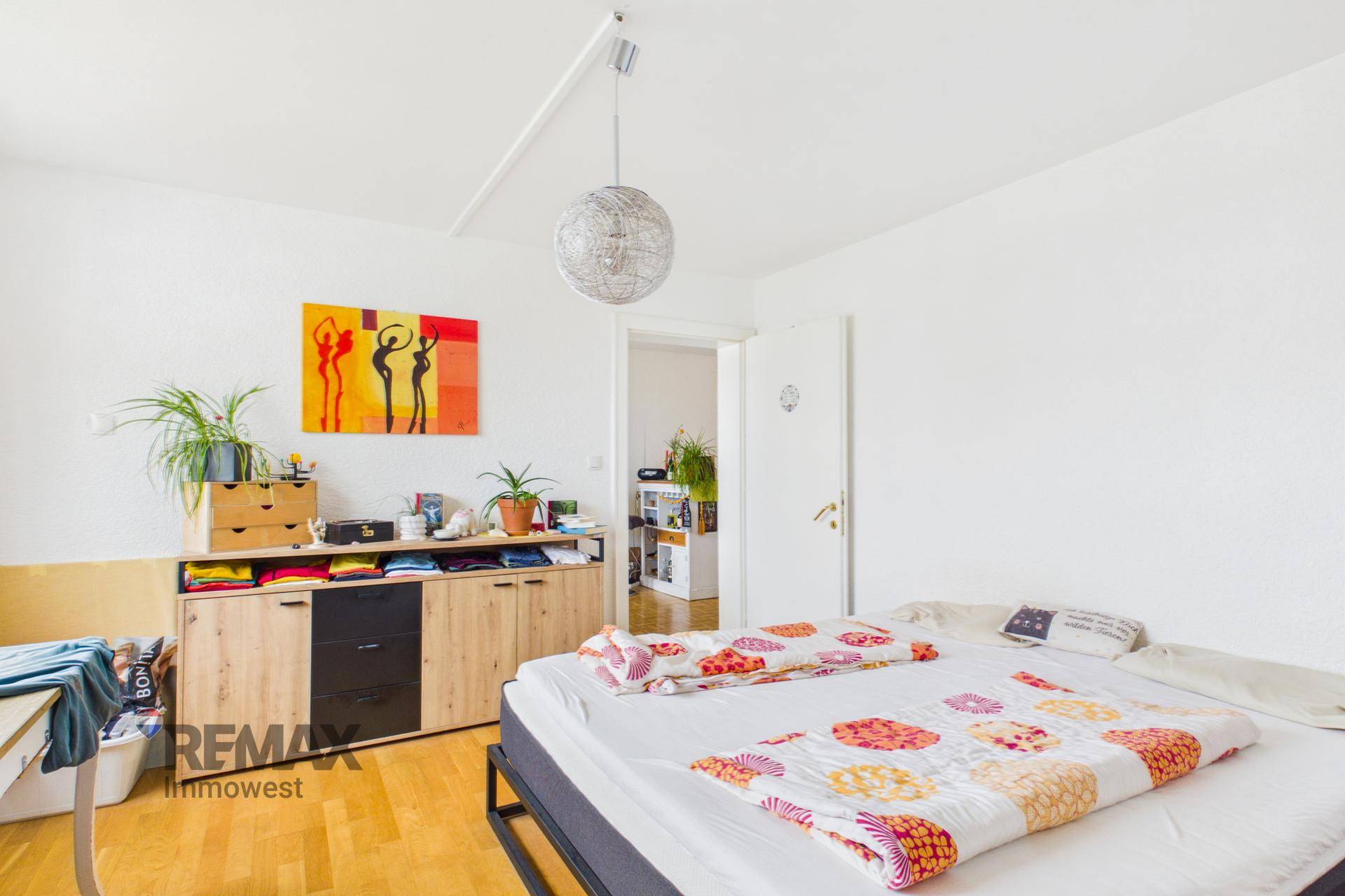 Schlafzimmer mit Parkettboden, modernem Sideboard und Zugang zu einem weiteren Raum.