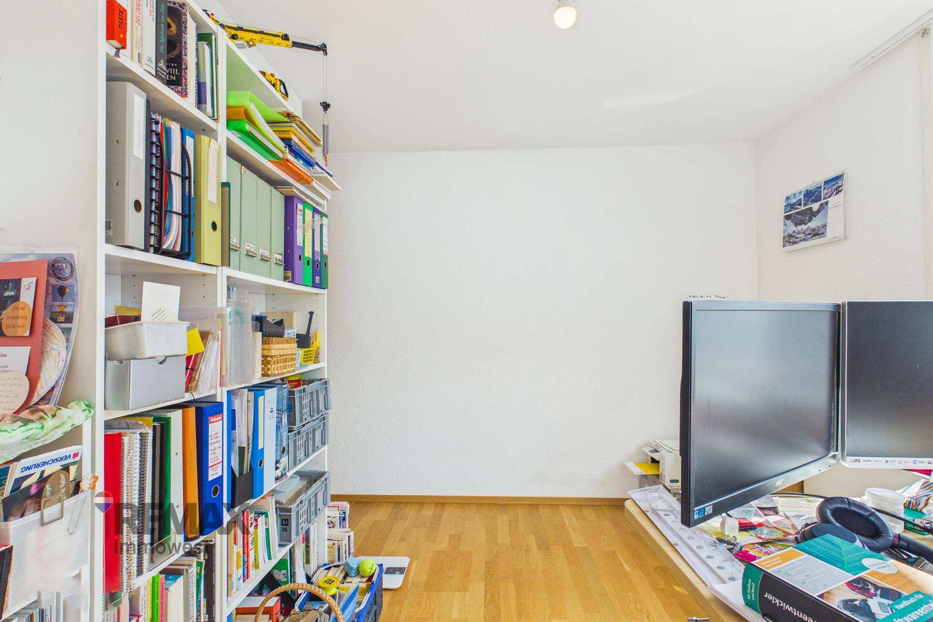 Arbeitszimmer mit großem Bücherregal und Parkettboden.