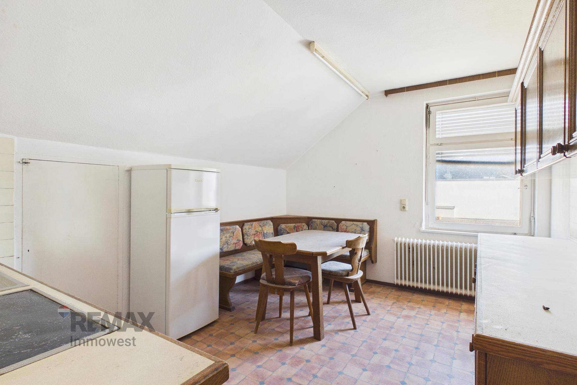 Küche im Dachgeschoss mit Essbereich, Kühlschrank und Fenster mit Blick nach draußen.