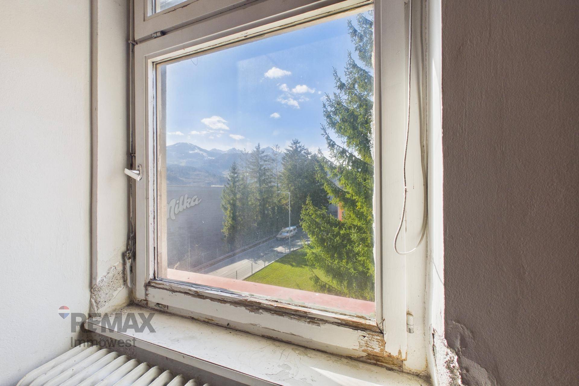 Fenster mit weitem Blick auf die Berge und die umliegende grüne Landschaft.