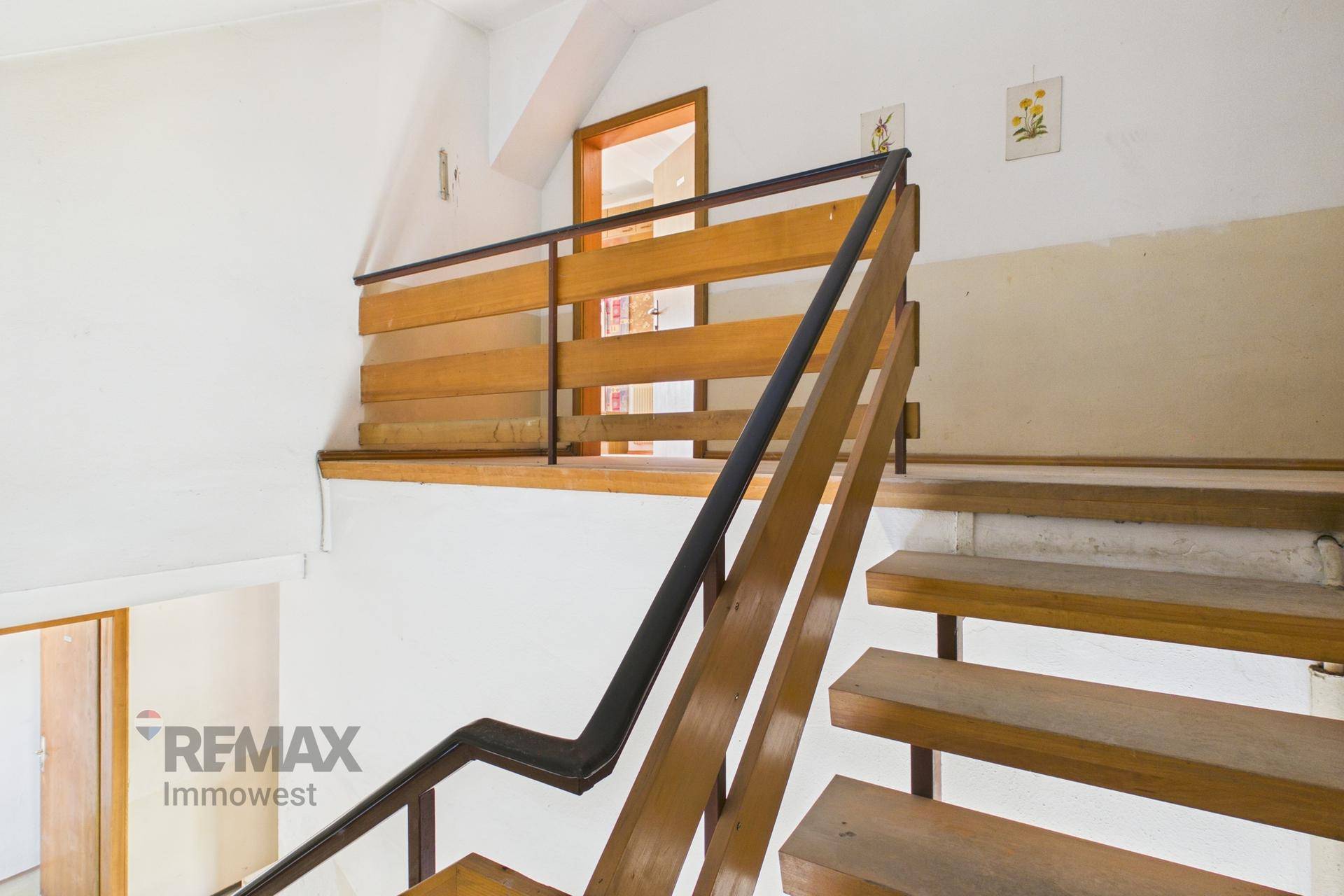 Holztreppe mit Geländer, die zu einem oberen Bereich des Hauses führt.