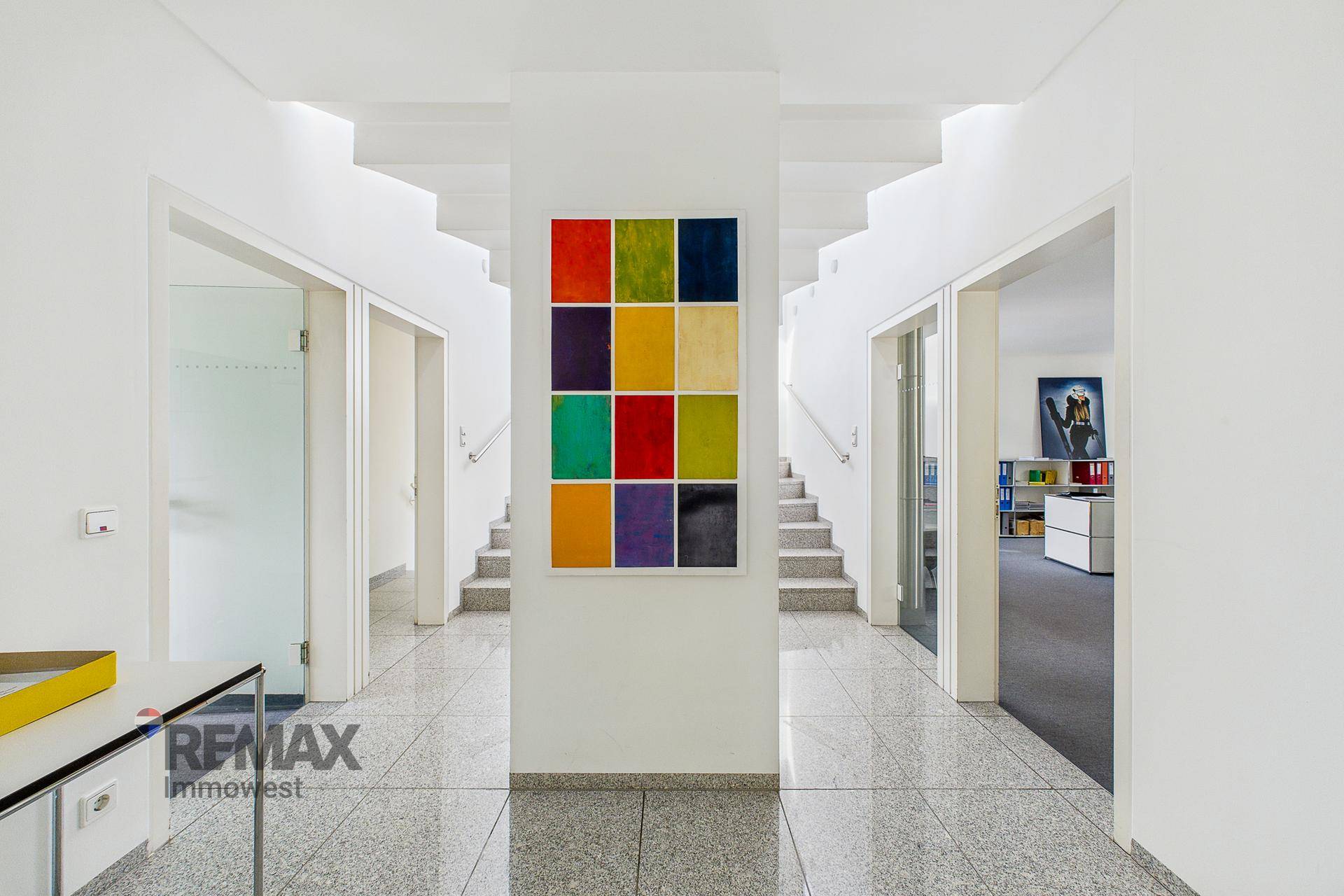 Geräumiger Flur mit Granitboden und farbenfrohem Kunstwerk, der den Zugang zu mehreren Büros ermöglicht.