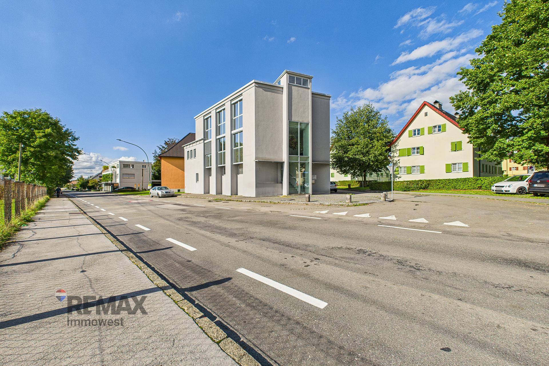 Ansicht des modernen Bürogebäudes von der Straße aus, umgeben von Bäumen und anderen Häusern.