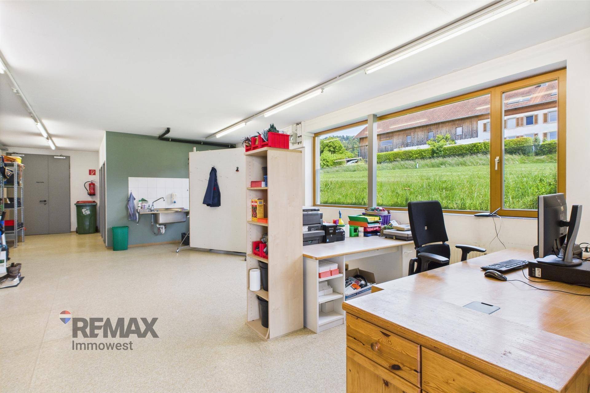Geräumiges Büro mit Arbeitsplätzen, Regalen und großen Fenstern mit Blick auf die Landschaft.