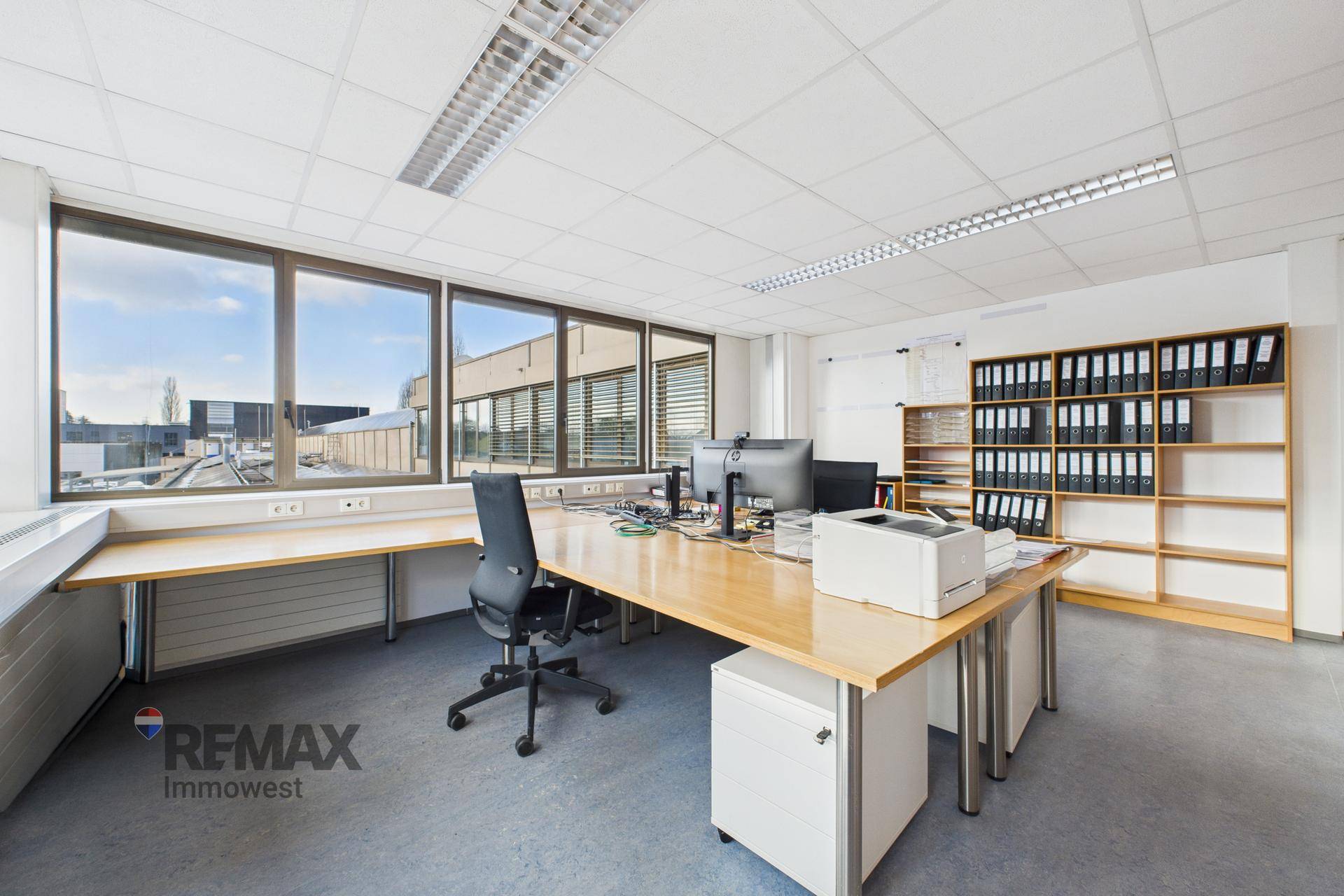 Helles Büro mit großem Schreibtisch, Bürostuhl und Blick auf die Umgebung.