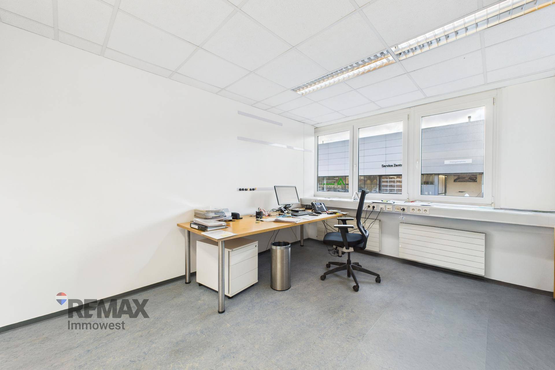 Geräumiges Büro mit Schreibtisch, Bürostuhl und Fenstern mit Jalousien.