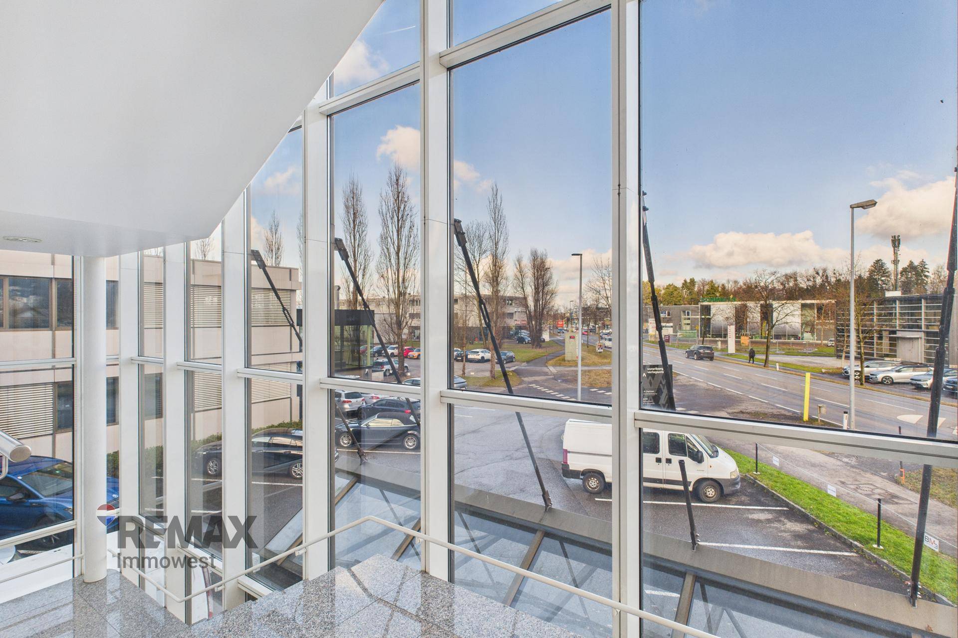 Heller Eingangsbereich mit großer Glasfassade und Blick auf die Straße und den Parkplatz.