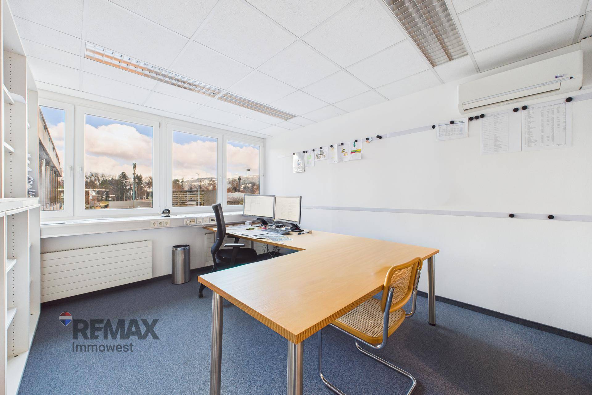 Büro mit Schreibtisch, Bürostuhl und Klimaanlage an der Wand, bietet Komfort.