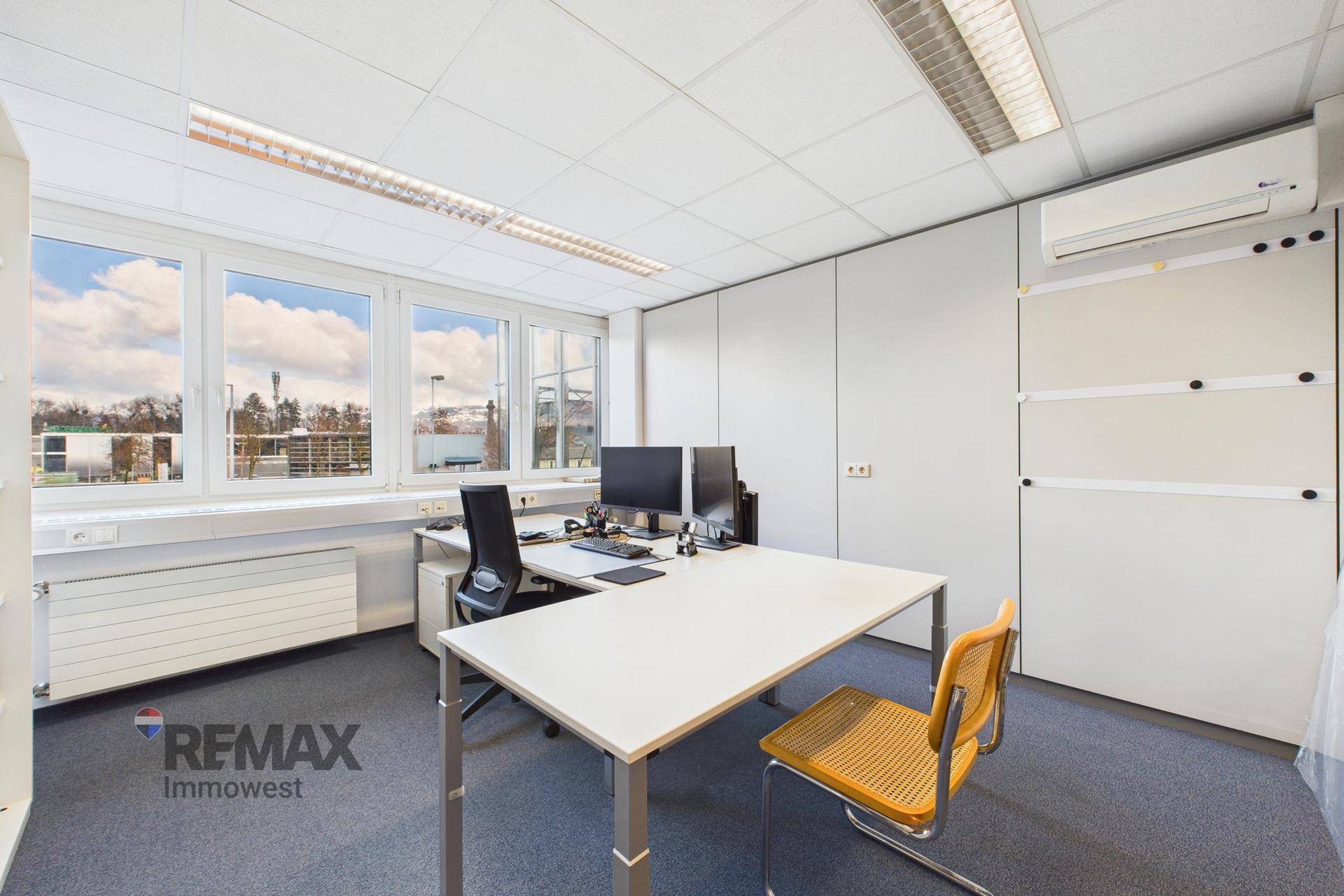 Büro mit Schreibtisch, Bürostuhl und Klimaanlage an der Wand, bietet Komfort.
