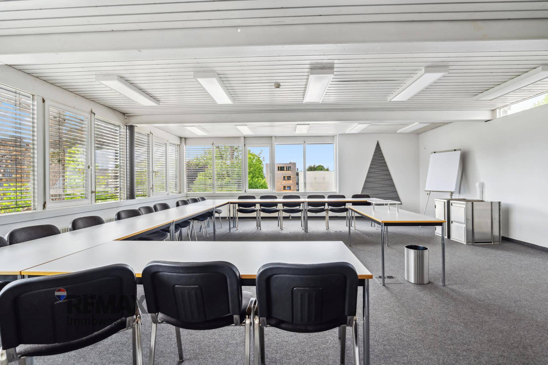 Großer Konferenzraum mit U-förmiger Tischordnung, Teppichboden und vielen Fenstern für Besprechungen.