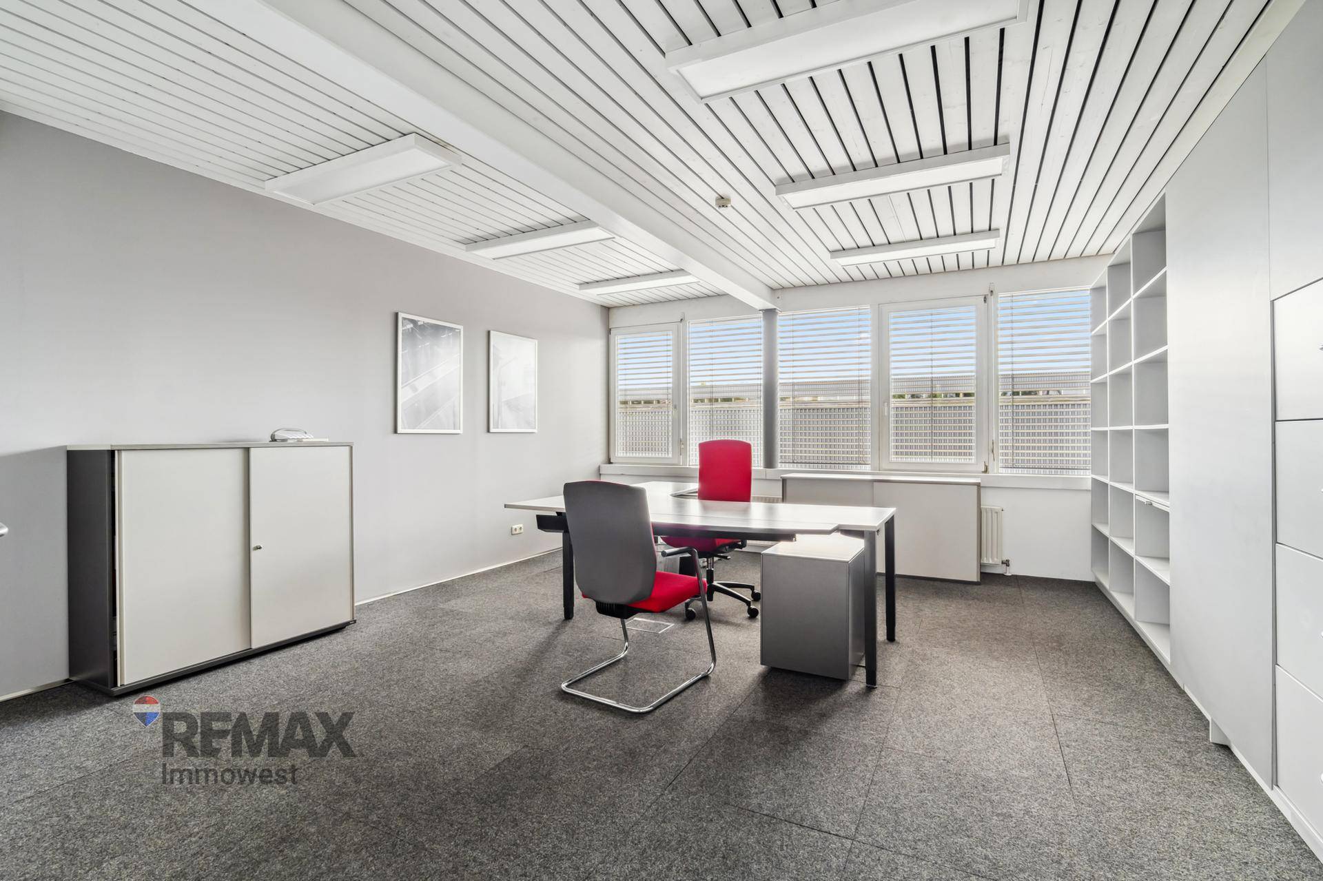 Einzelbüro mit Teppichboden, Schreibtisch, Bürostuhl und integrierten Regalen für Organisation.