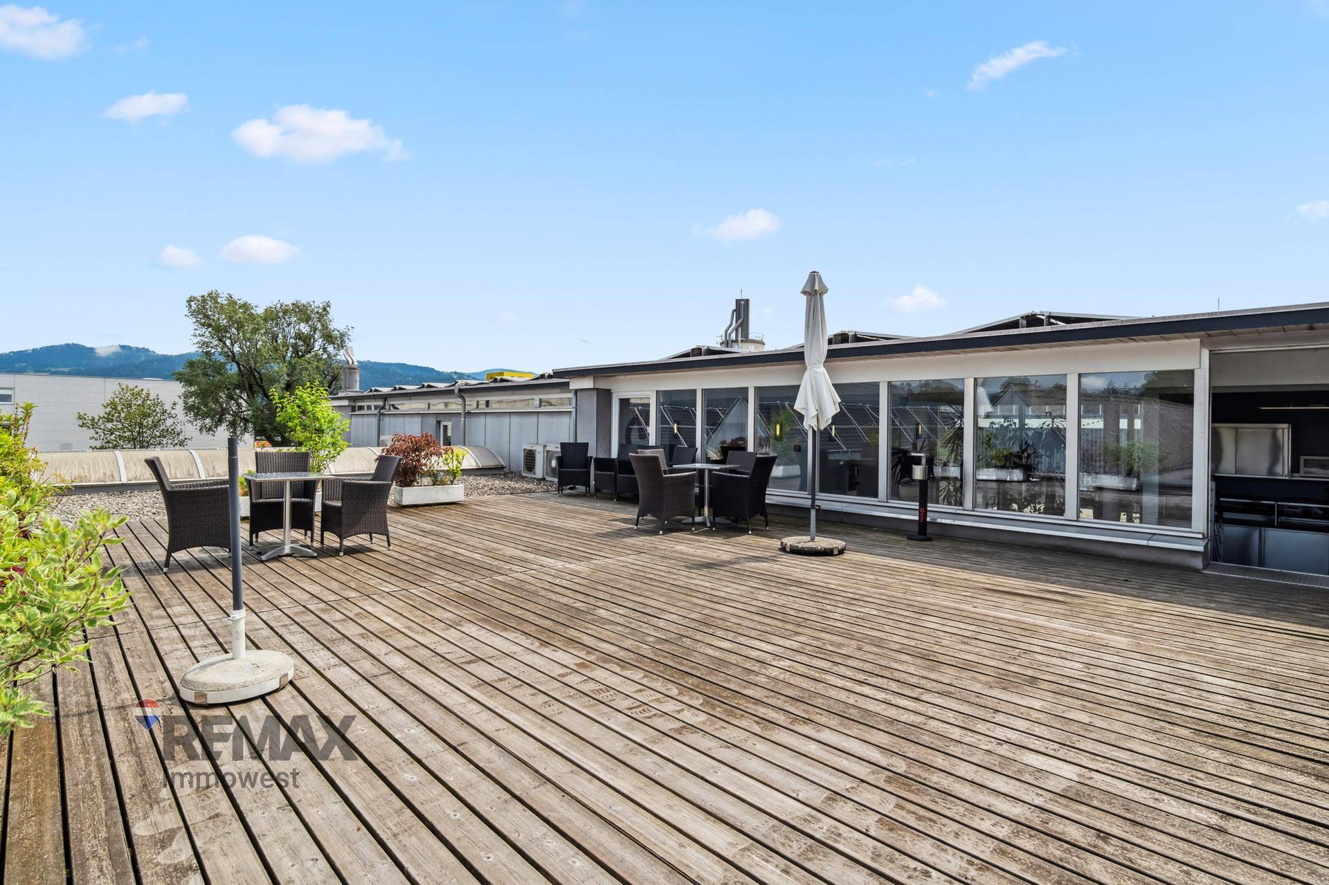 Weitläufige Dachterrasse mit Holzboden und Sitzbereichen, ideal für Pausen und Entspannung im Freien.