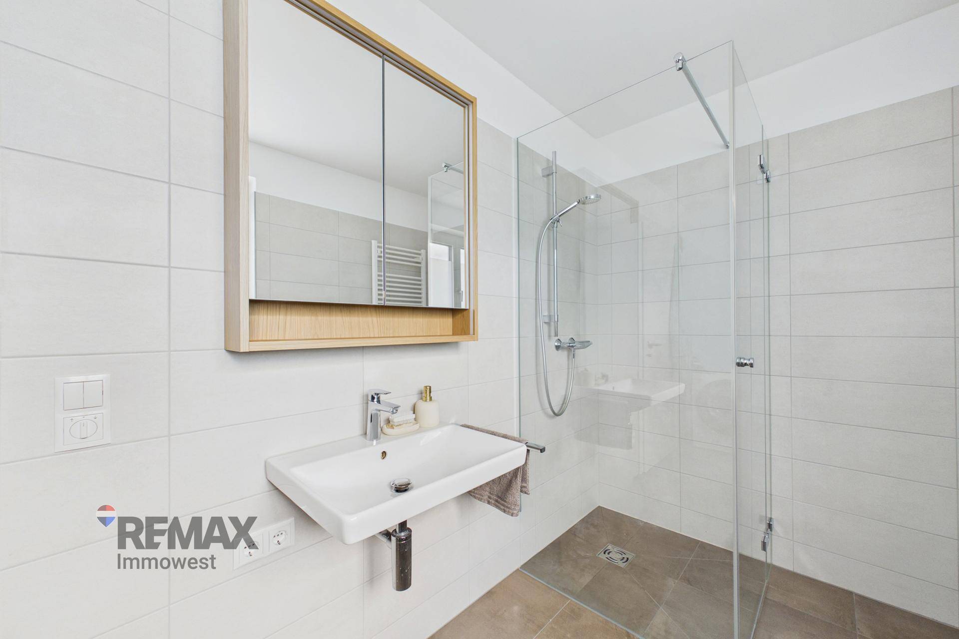 Modernes Badezimmer mit ebenerdiger Dusche, Waschbecken und Spiegelschrank.