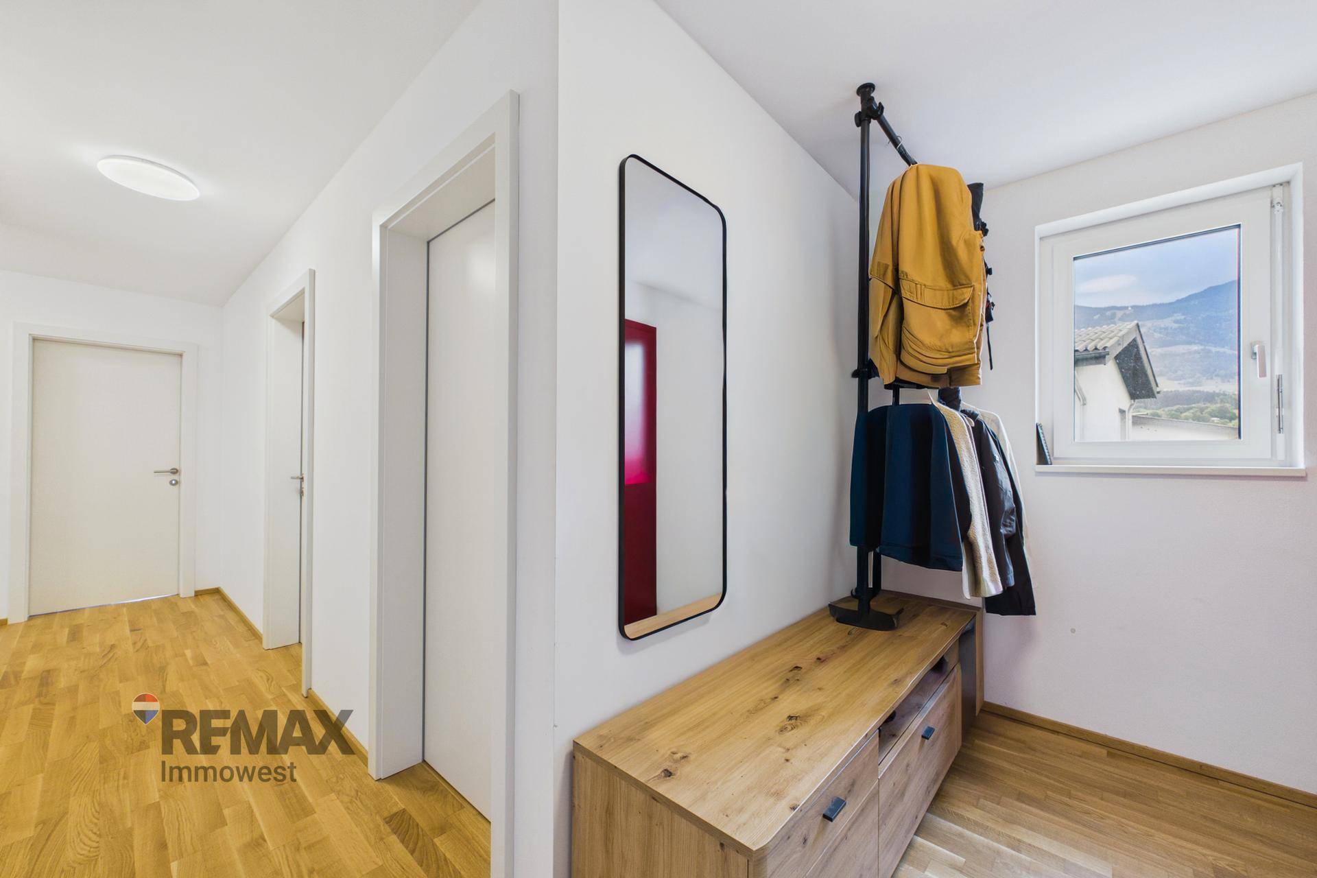 Eingangsbereich mit Garderobe, Spiegel und hellem Holzparkettboden.