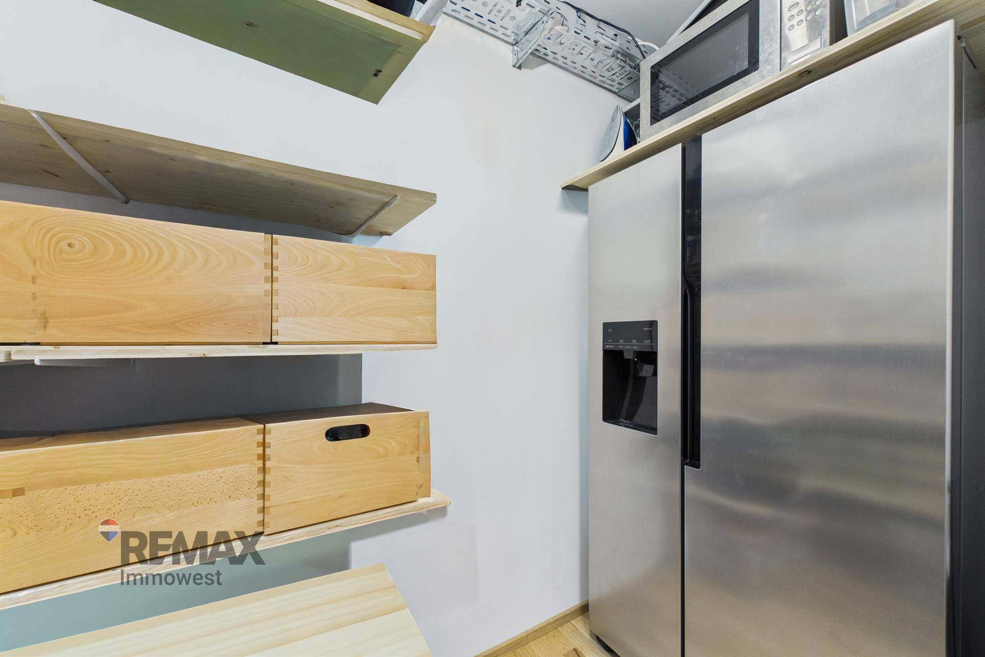 Praktischer Abstellraum mit Regalen und großem Kühlschrank.