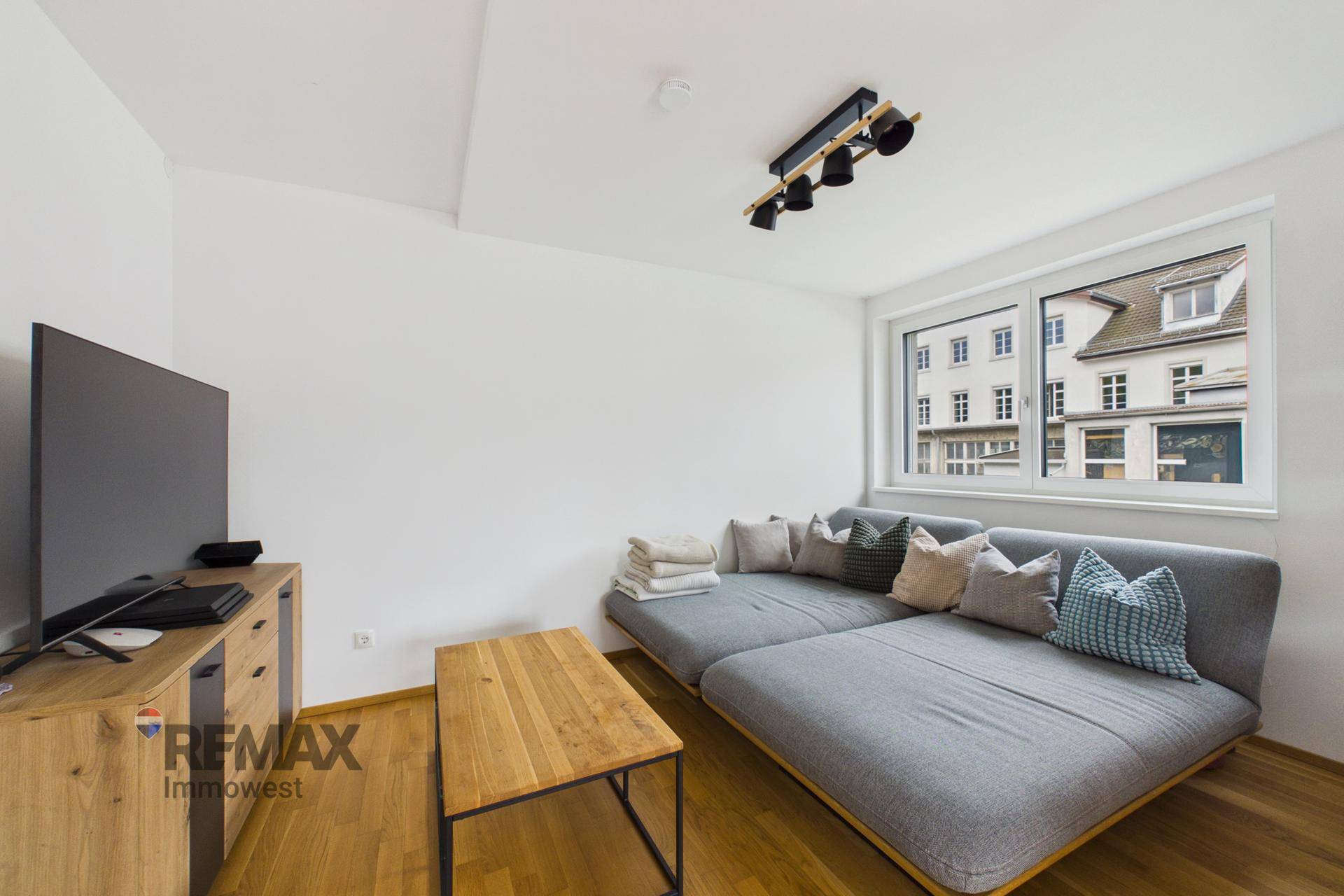 Gemütliches Wohnzimmer mit großem Sofa, Fernseher und Holzboden.
