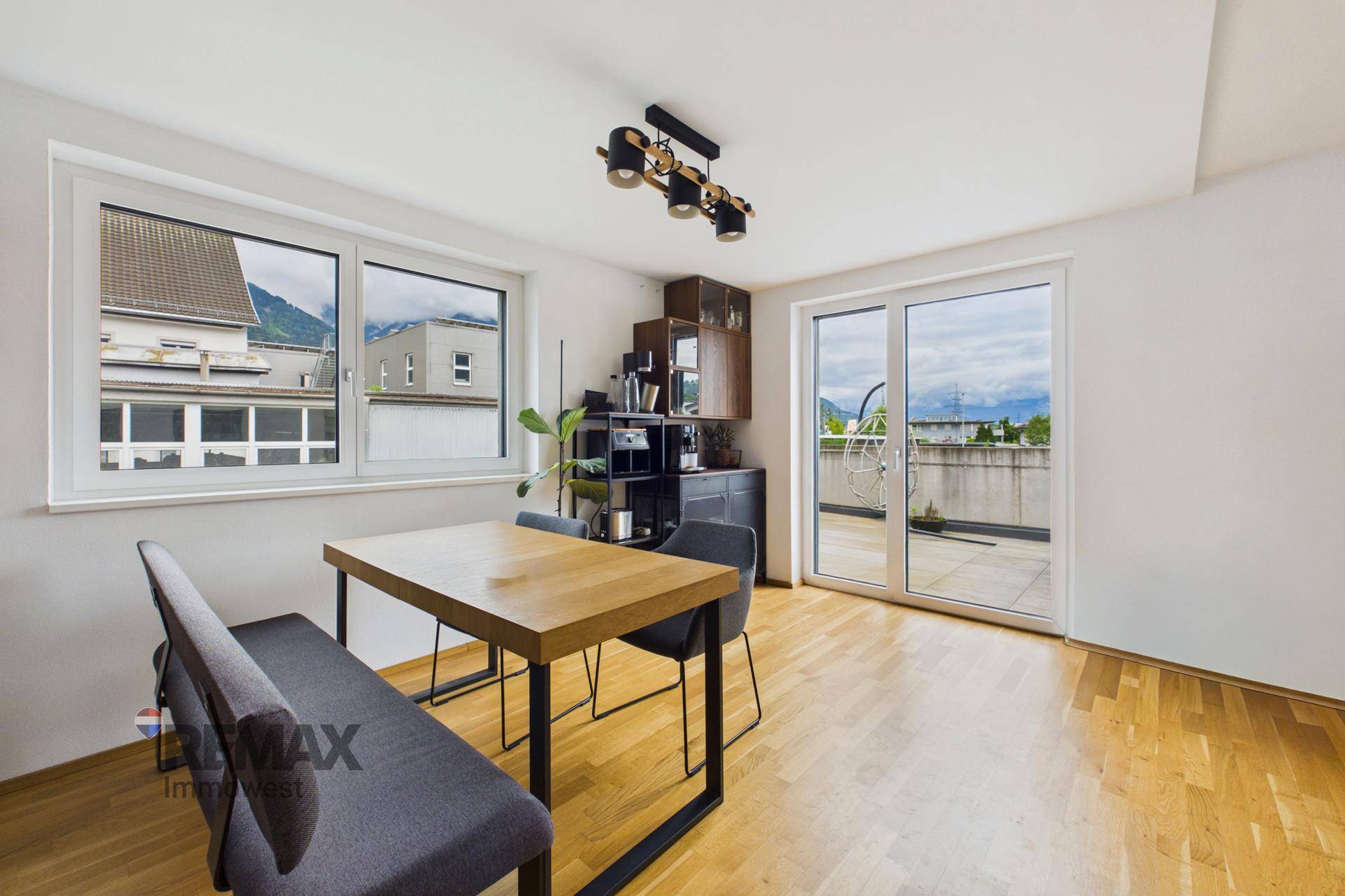 Heller Essbereich mit Holztisch, Sitzbank und Zugang zur Dachterrasse.