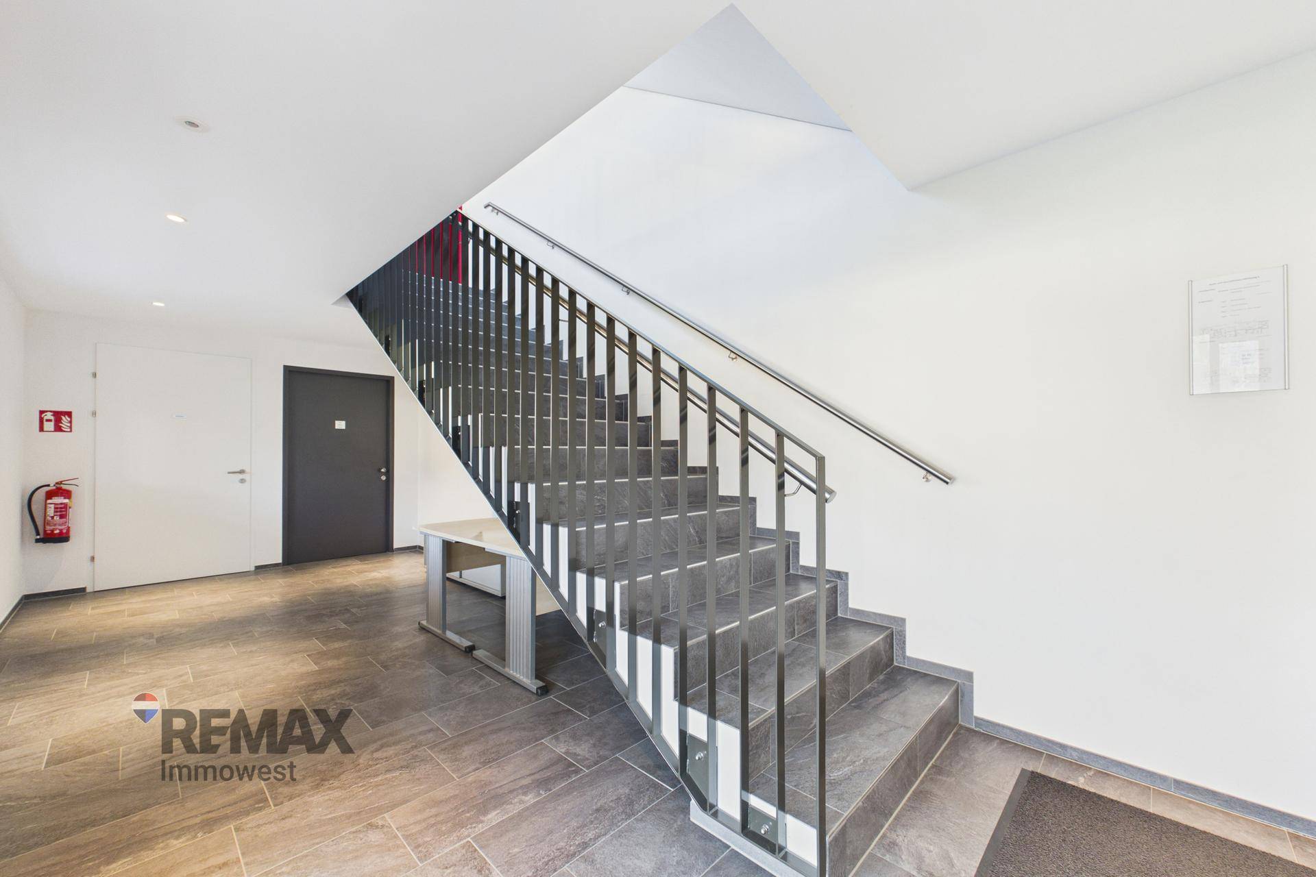 Treppenhaus mit modernem Geländer und Fliesenboden.