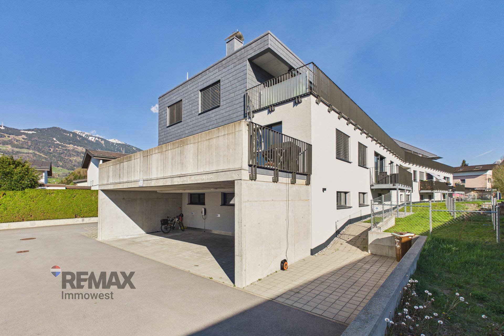 Modernes Mehrfamilienhaus mit Tiefgarage, Balkonen und Grünflächen in der Umgebung.