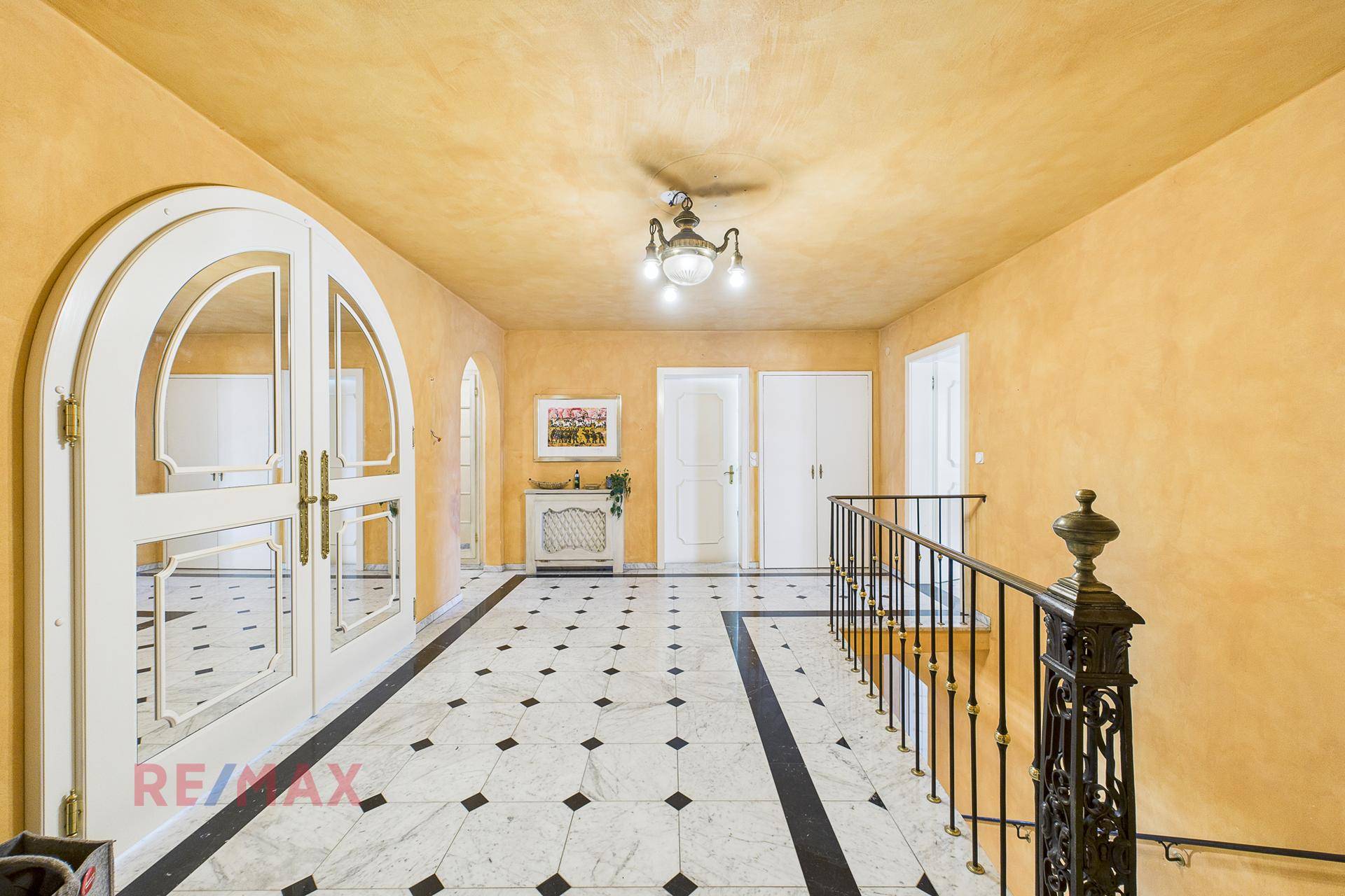 Geräumiger Flur mit gelben Wänden, Marmorboden und eleganter Treppe.