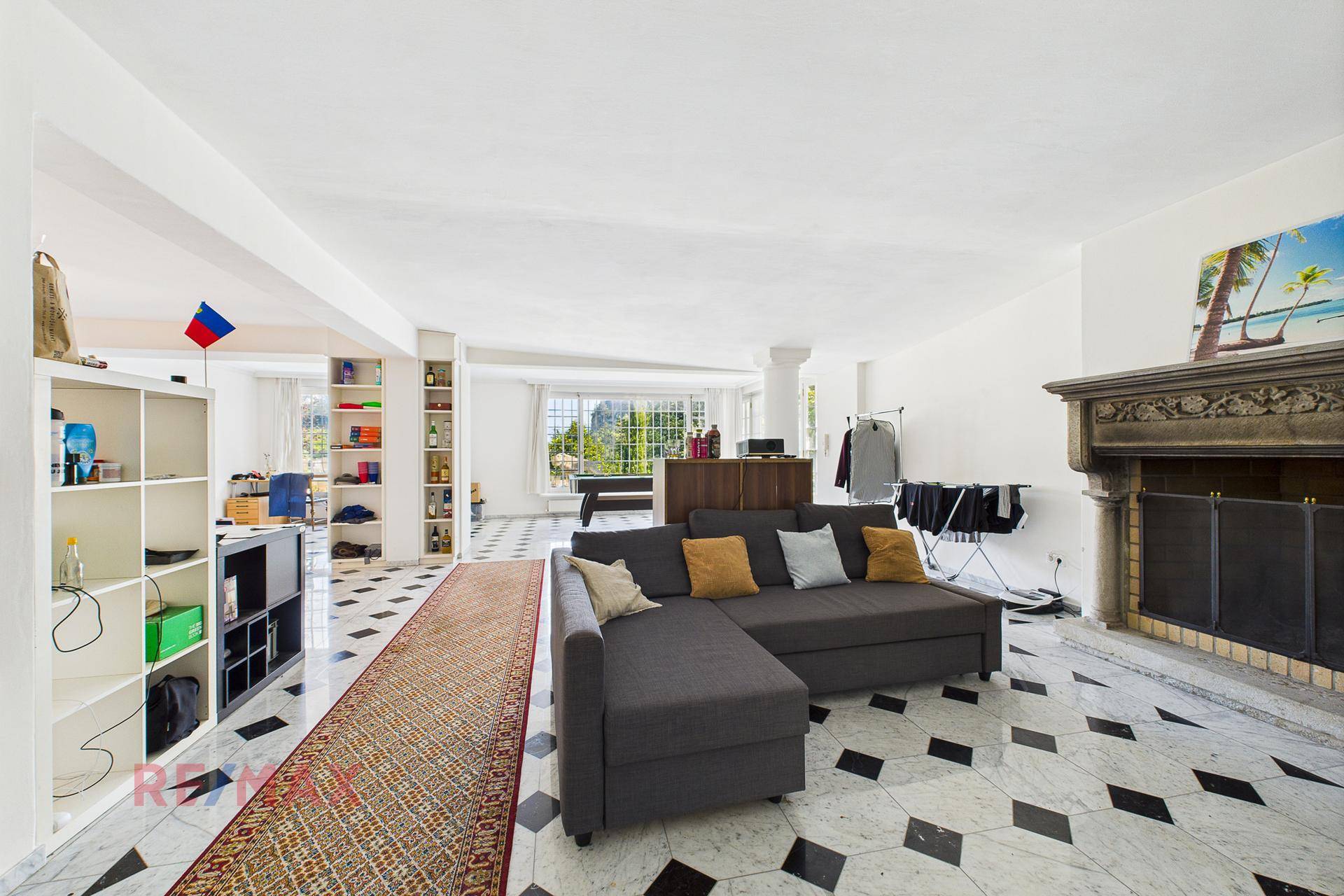 Heller Wohnbereich mit Marmorboden, großem Sofa und einem dekorativen Kamin.