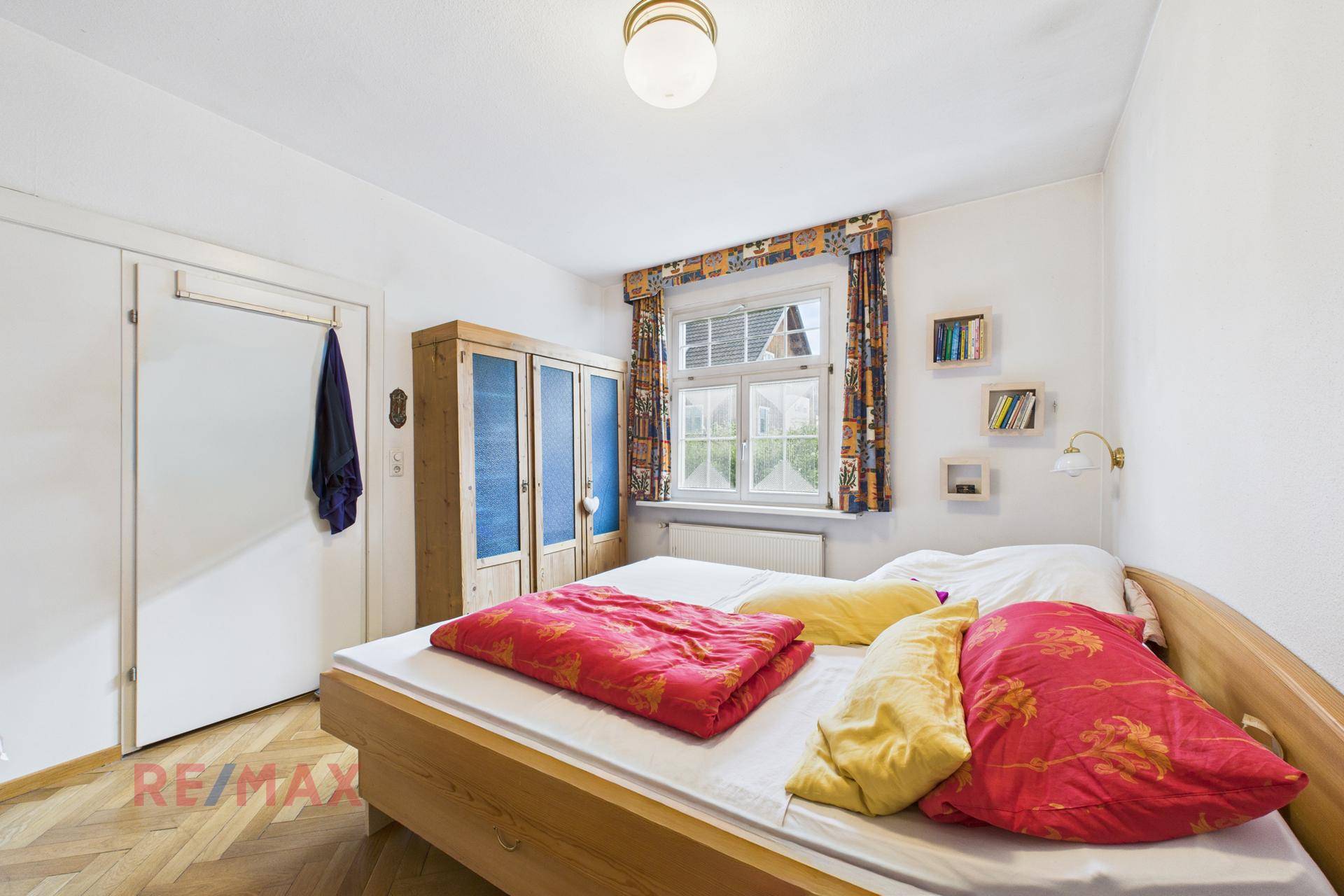 Schlafzimmer mit Holzbett, Parkettboden und einem Kleiderschrank aus Holz.