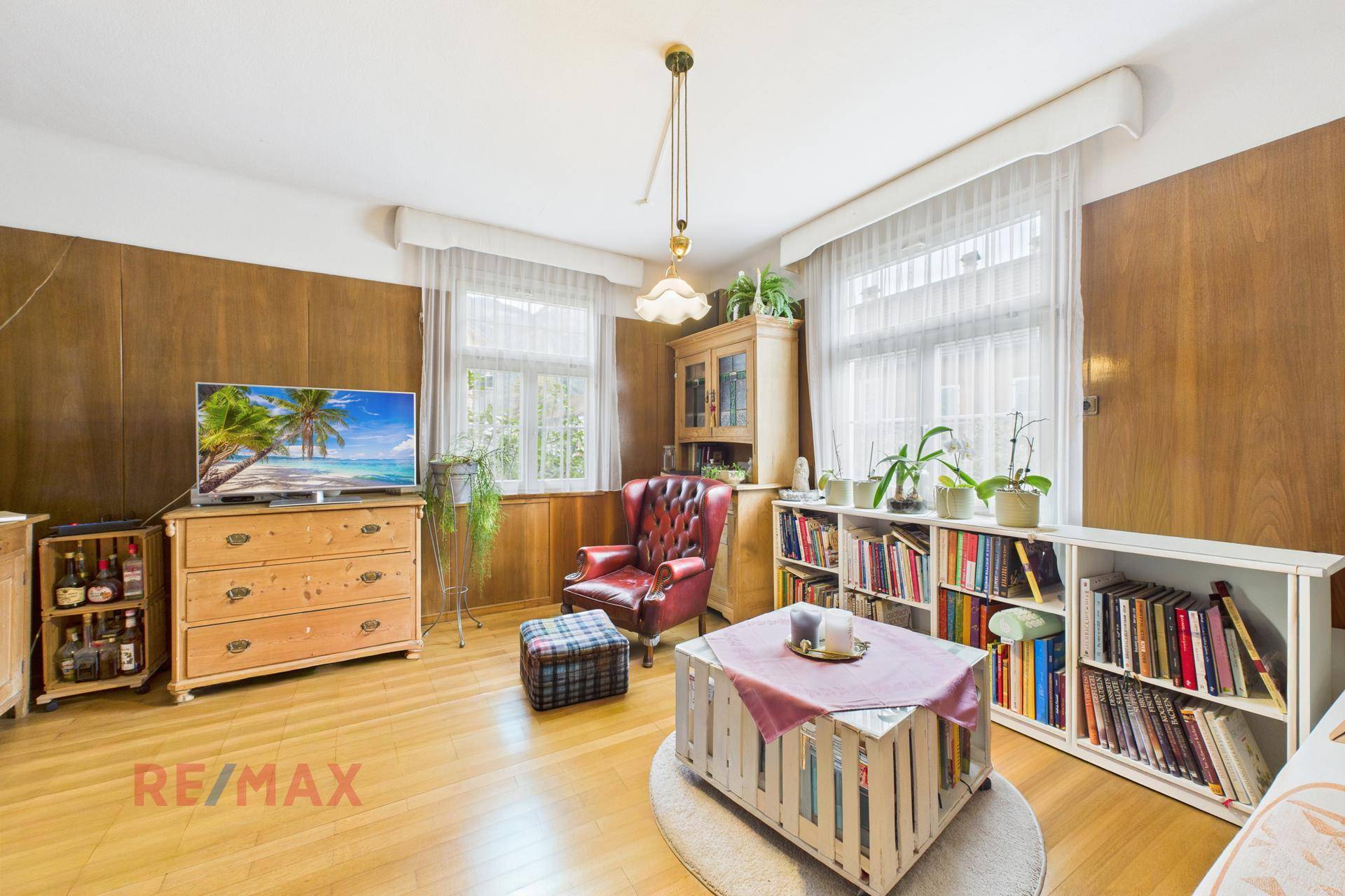 Wohnzimmer mit Holzboden, Bücherregalen und einem Fernseher auf einer Kommode.